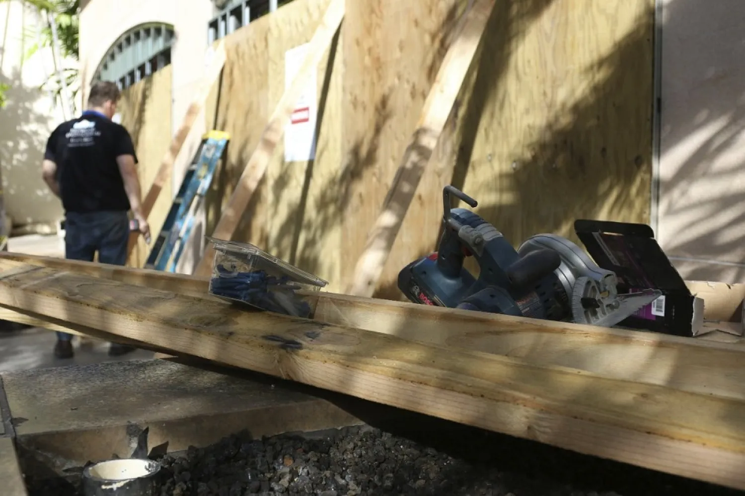 A worker puts reinforcements on boarded storefront windows in the Waikiki neighborhood of Honolulu, Saturday, July 25, 2020, as Hurricane Douglas approaches. (AP)