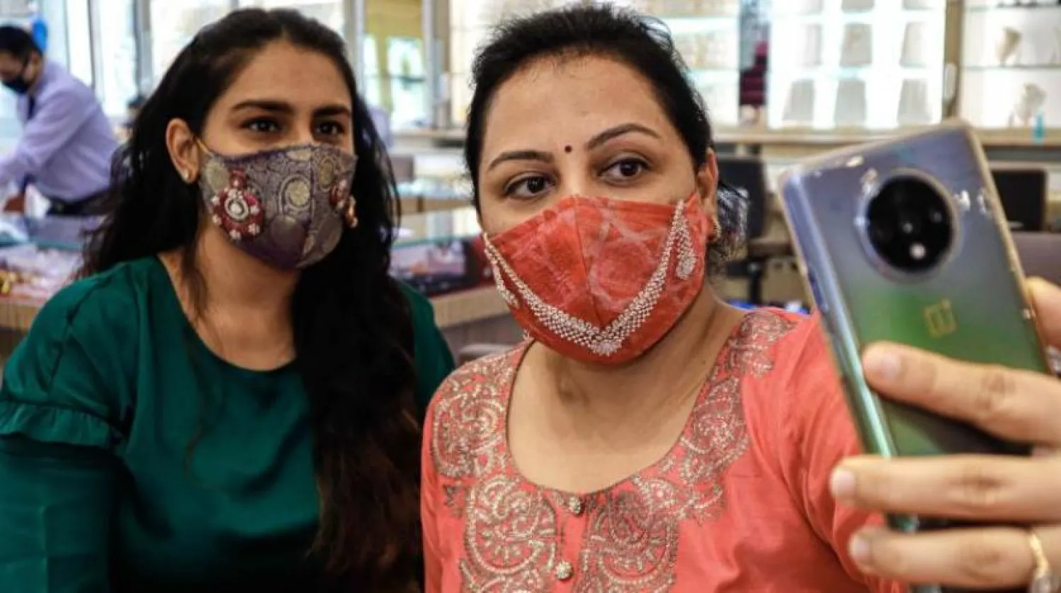 Hindistan’da maske takan iki kadın selfie çekerken (AFP)