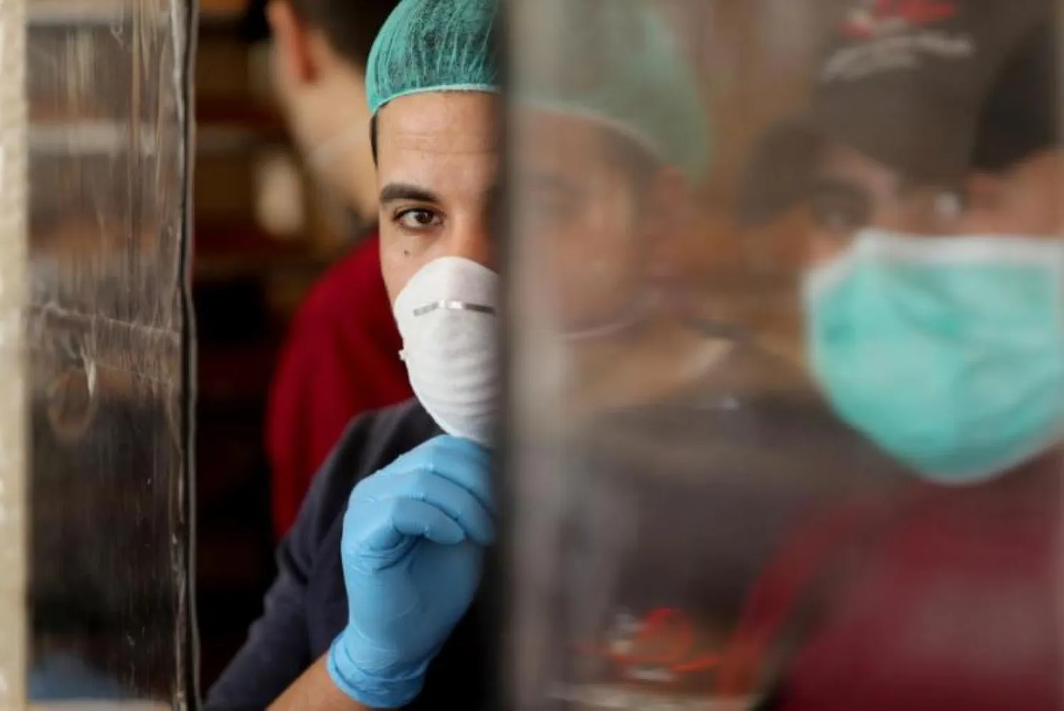 فلسطينيون يرتدون أقنعة الوقاية خلال عملهم في مخبز بمدينة غزة (أرشيفية - رويترز)