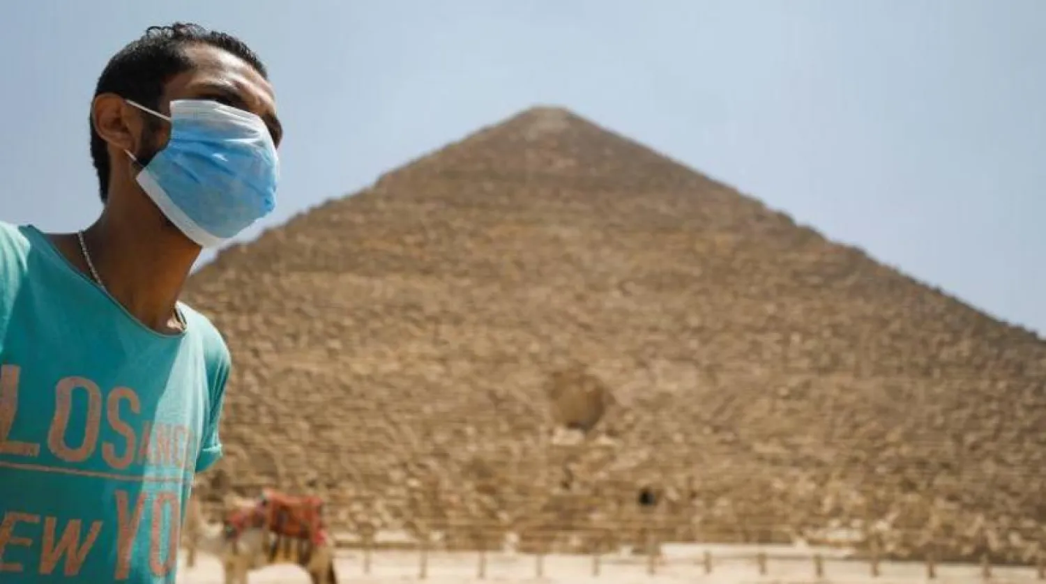 Gize’deki piramitler bölgesinde koronavirüsten korunmak için maske takmış bir genç (Reuters)