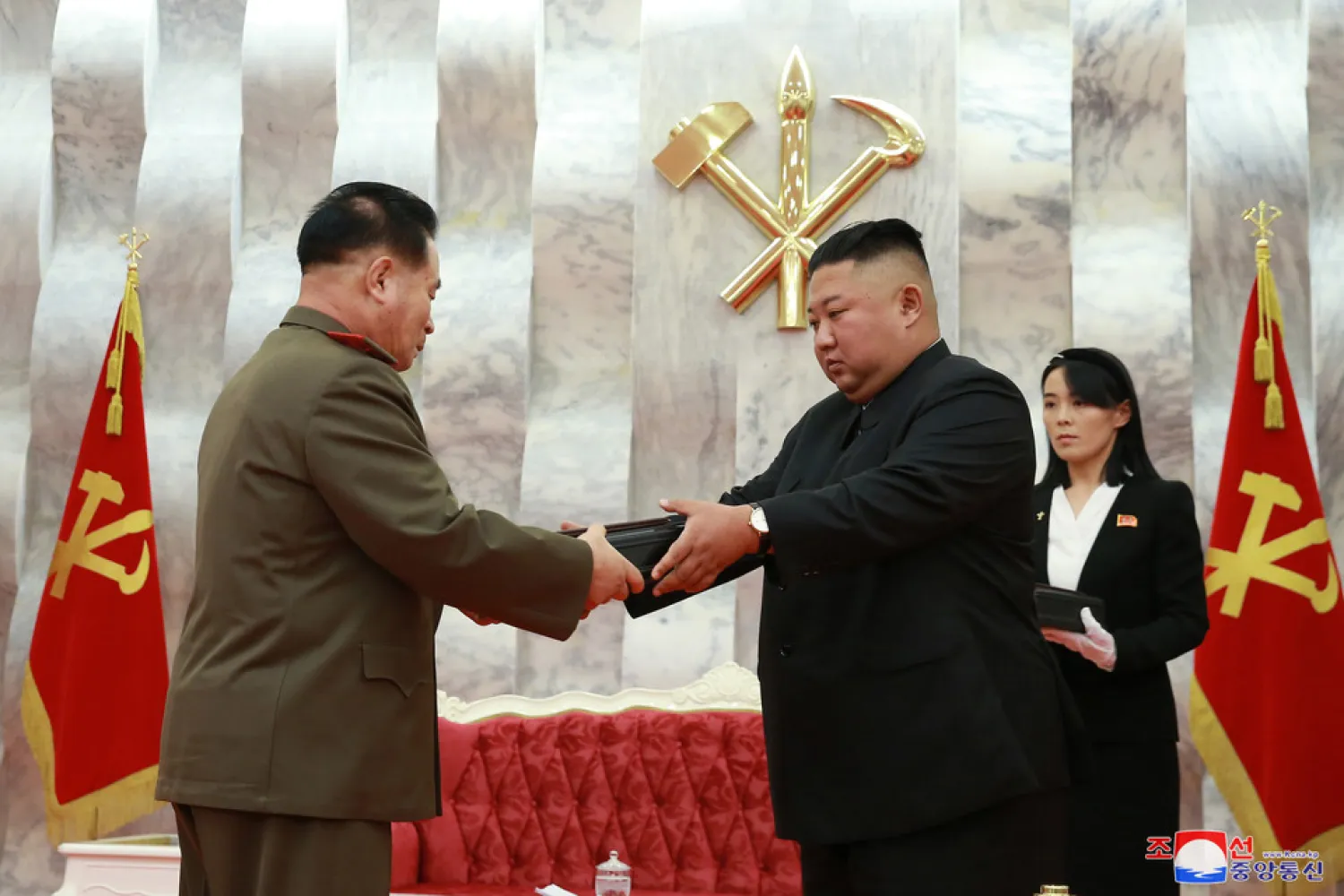 In this Sunday, July 26, 2020, photo released by the North Korean government, North Korean leader Kim Jong Un, center, hands over a "Paektusan" commemorative pistol to a senior military official during a ceremony in Pyongyang, North Korea. At right is Kim's powerful sister Kim Yo Jong. (Korean Central News Agency/Korea News Service via AP)