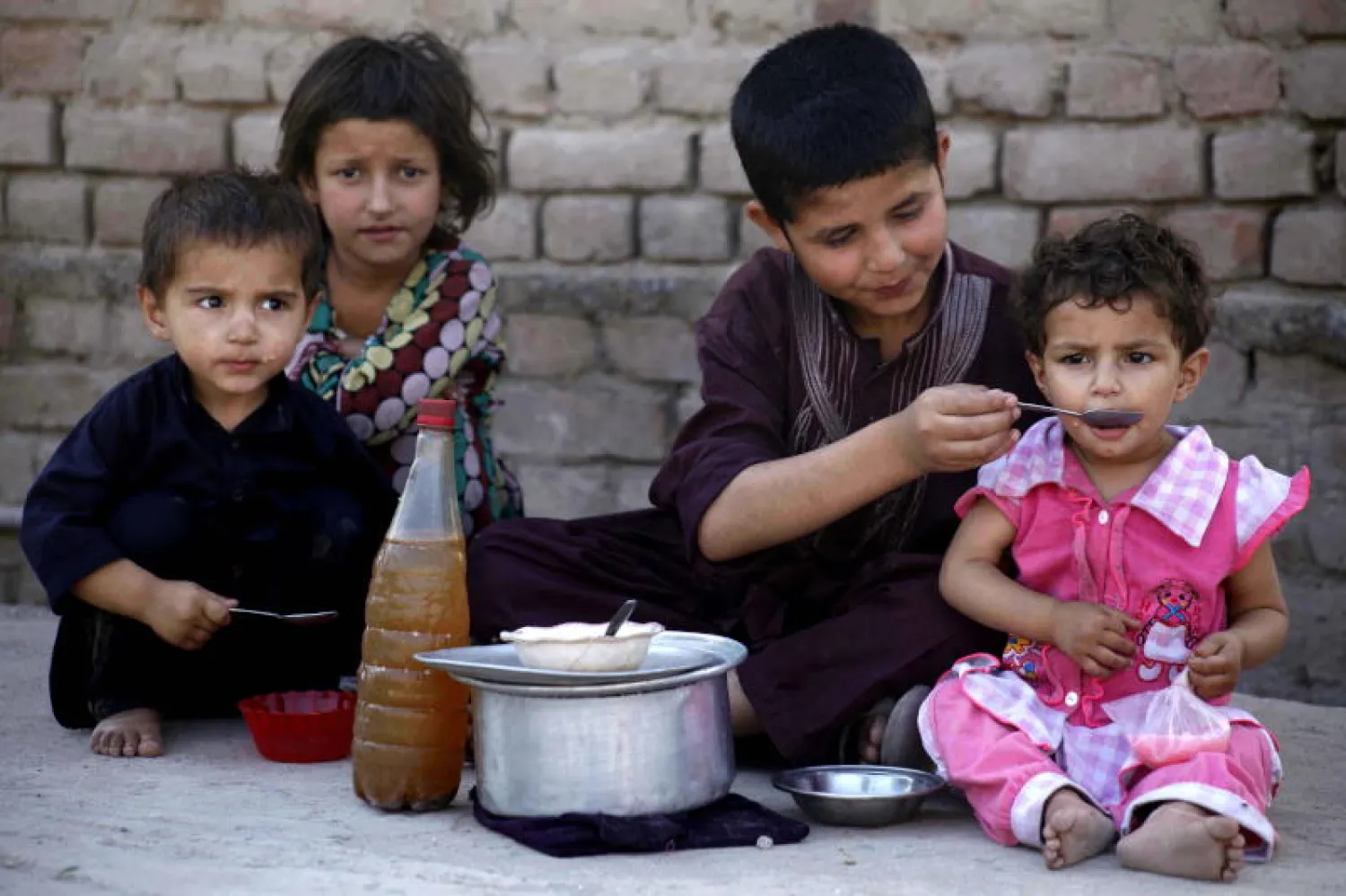 أطفال يأكلون على جانب الطريق في بيشاور الباكستانية (إ.ب.أ)