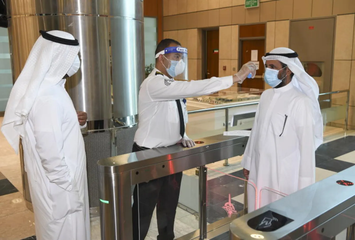 رجل أمن يتحقق من درجة حرارة العملاء بمدخل مركز تسوق بمدينة الكويت (إ.ب.أ)