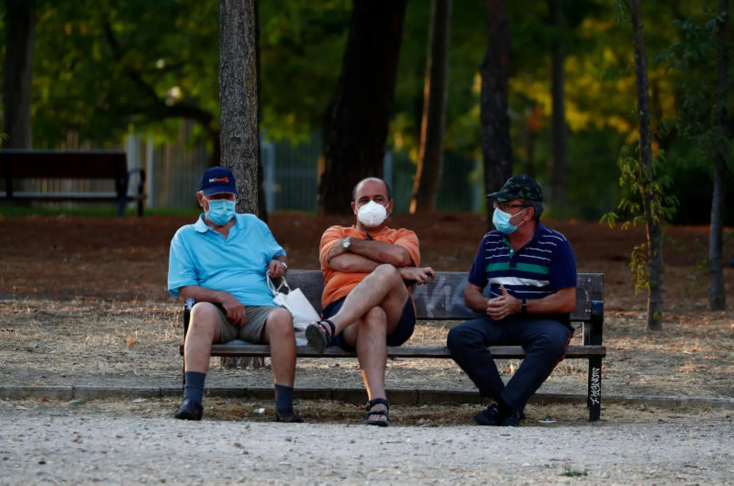 أشخاص يضعون كمامات في إحدى حدائق مدريد (رويترز)