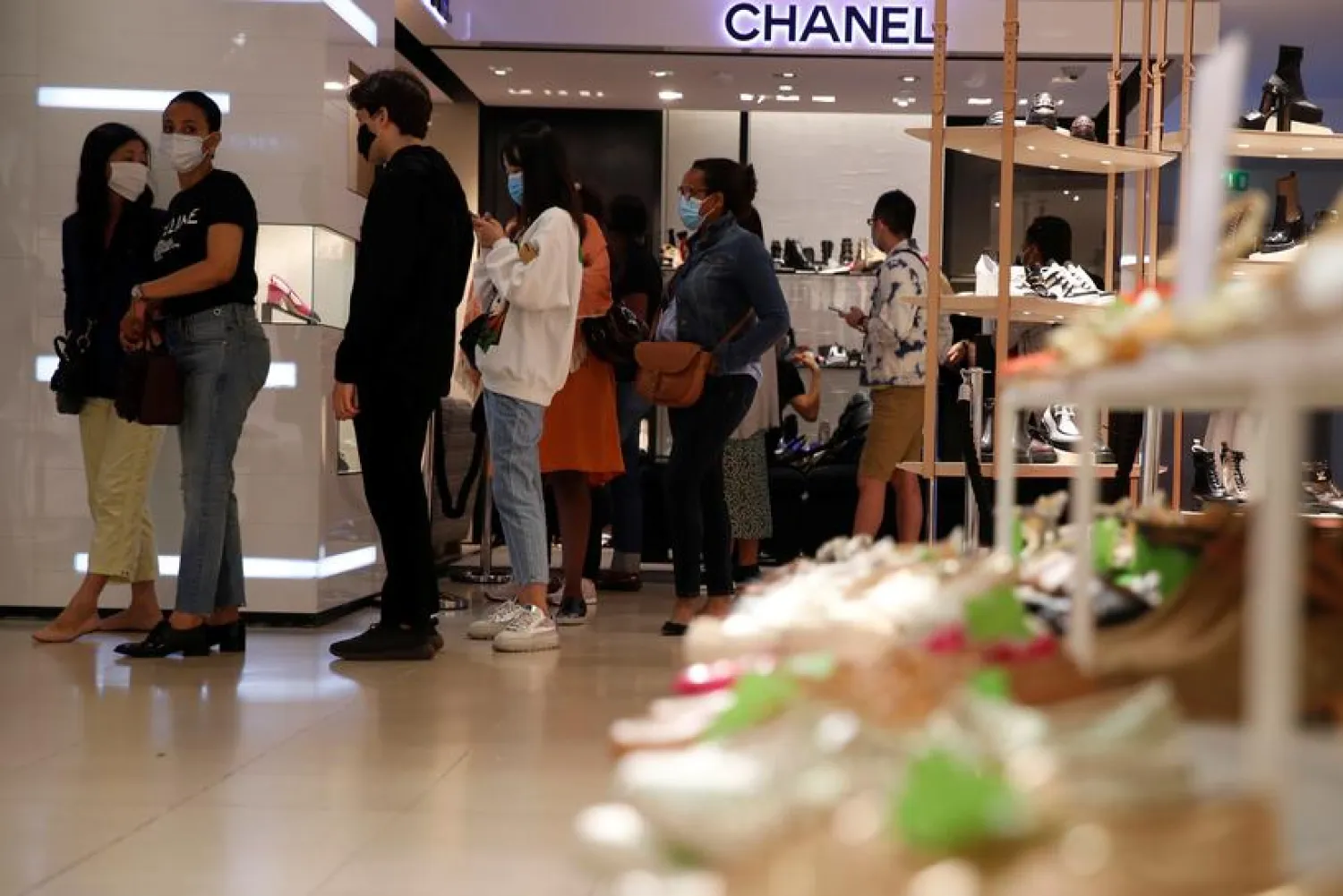 Customers, wearing protective face masks, line up in front of a Chanel shop inside the department store Le Printemps Haussmann in Paris on the first day of summer sales following the outbreak of the coronavirus disease (COVID-19) in France, July 15, 2020. REUTERS/Gonzalo Fuentes