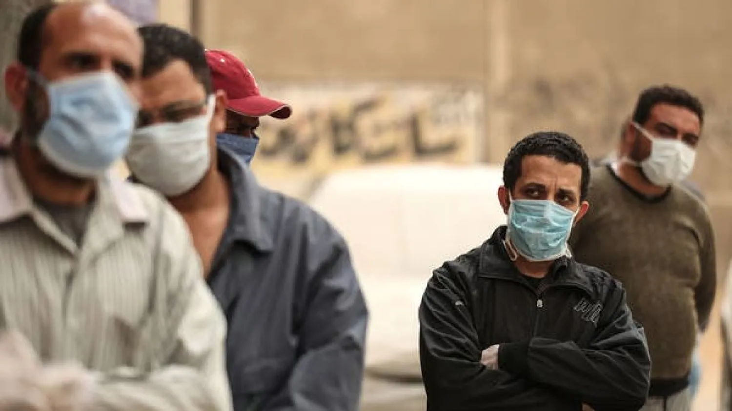 Egyptian men wearing masks wait outside a center of the non-governmental organization Egyptian Food Bank in Cairo. (AFP)
