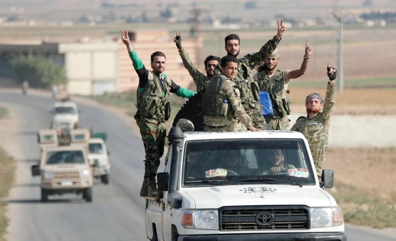 Turkey-backed Syrian fighters gesture as they ride on a vehicle near the border town of Tal Abyad, Syria, October 22, 2019. REUTERS/Khalil Ashawi TP
