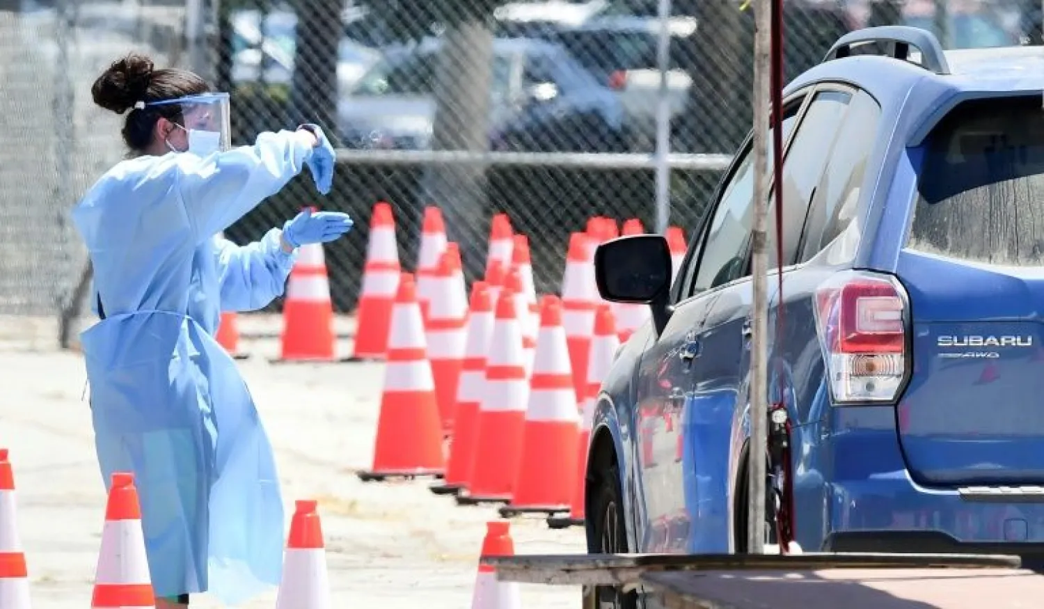 A volunteer gestures instructions to a driver at a COVID-19 test site on July 30, 2020 in the Panoramic City neighborhood of Los Angeles, California, where cases continue to spike | AFP