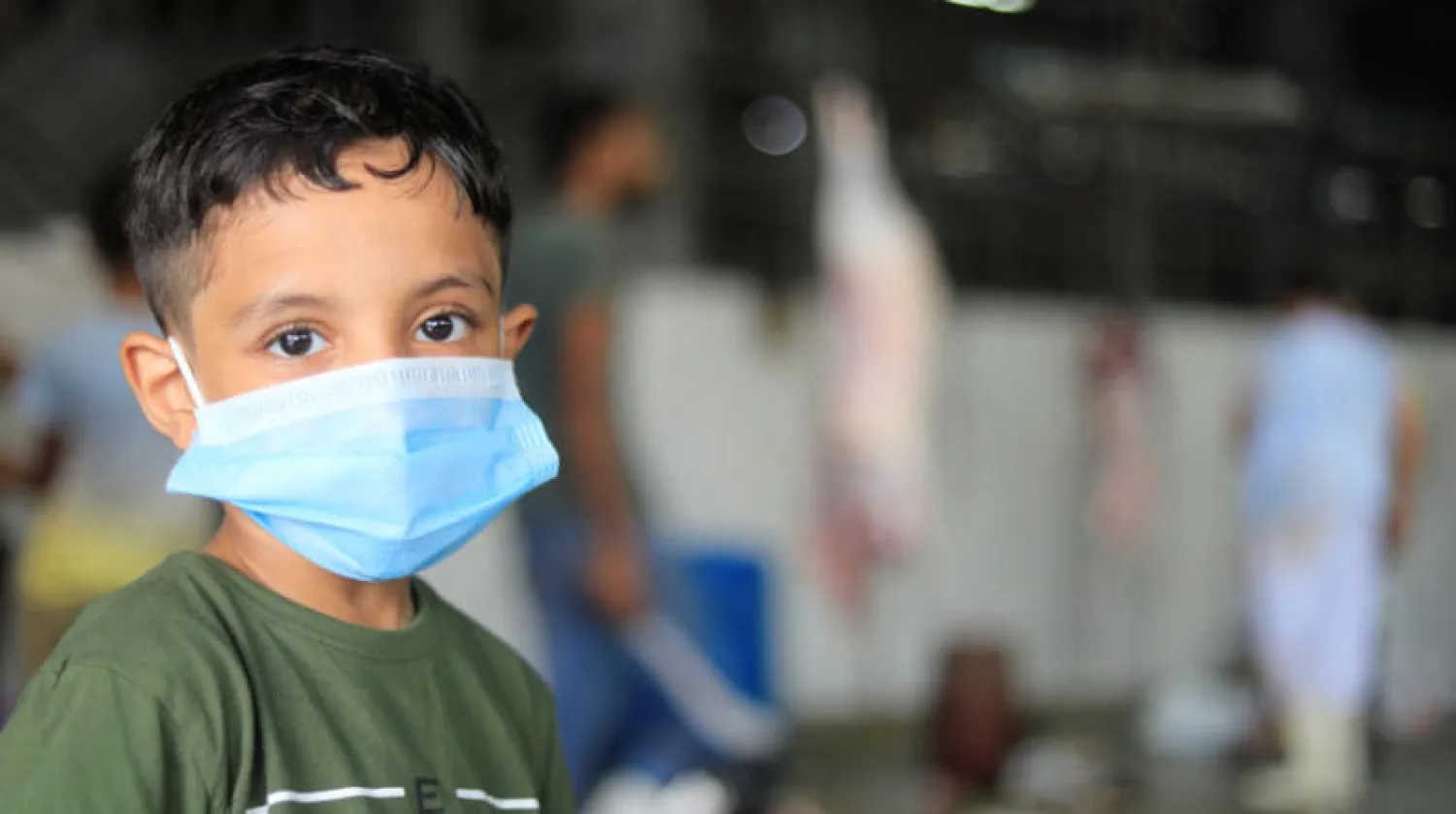 طفل يضع كمامة للوقاية من فيروس {كورونا} في مسلخ للحوم الأضاحي في القاهرة أمس (رويترز)