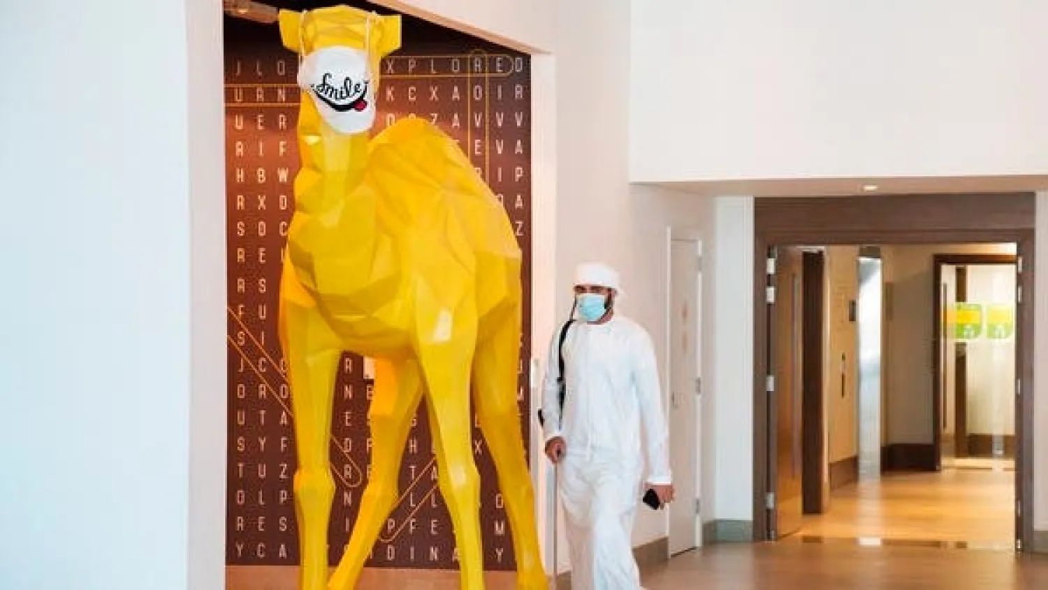 An Emirati walks past a camel statue decorated with a face mask at the Rove City Centre Hotel in Dubai. (File photo: AP)
