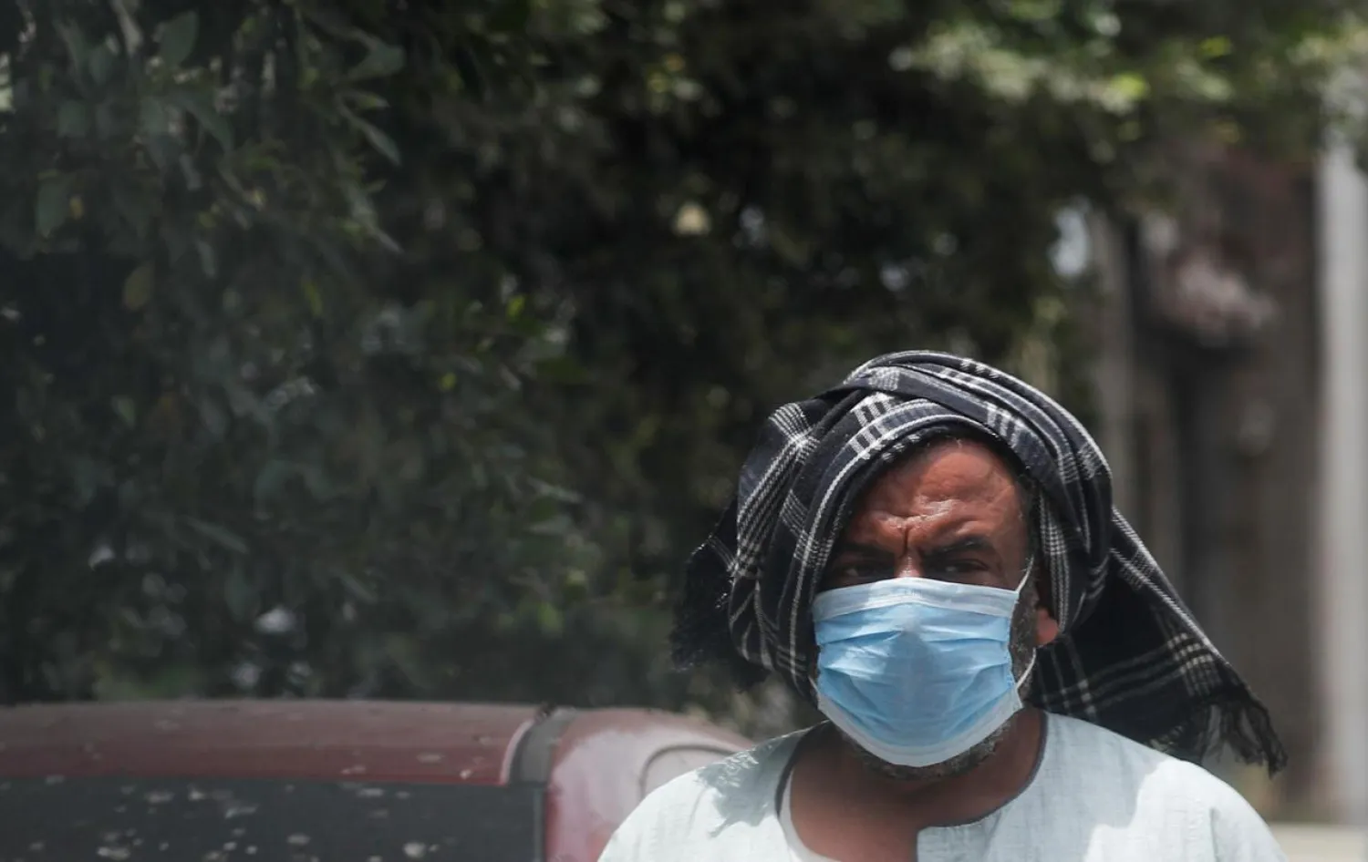 FILE PHOTO: A man wearing a protective face mask covers his head during a hot weather, amid concerns over the coronavirus disease (COVID-19), in Cairo, Egypt May 13, 2020. REUTERS/Amr Abdallah Dalsh