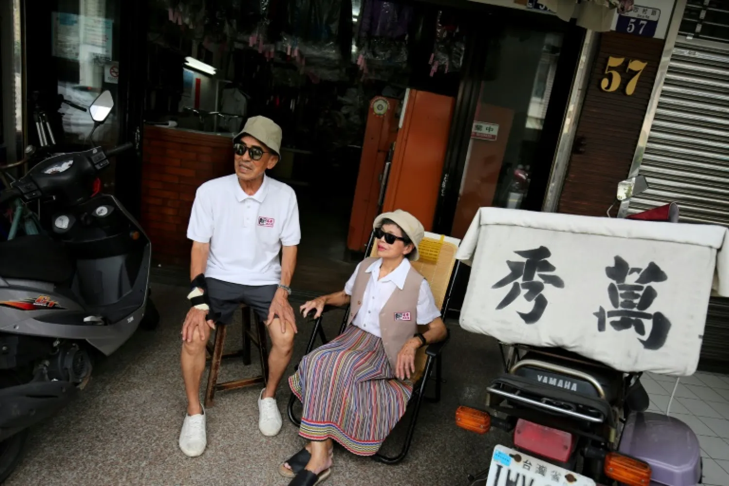 In this picture taken on July 30, 2020, Chang Wan-ji (L) and his wife Hsu Sho-er pose for photographs at their laundry store in Taichung. (Photo by HSU Tsun-hsu / AFP) 