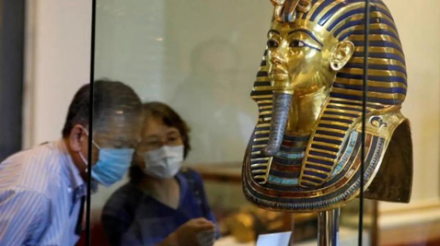 Koruyucu maske takan iki turist Mısır Müzesi'ndeki Tutankhamun'un altın maskesine bakıyor (Reuters-Arşiv)