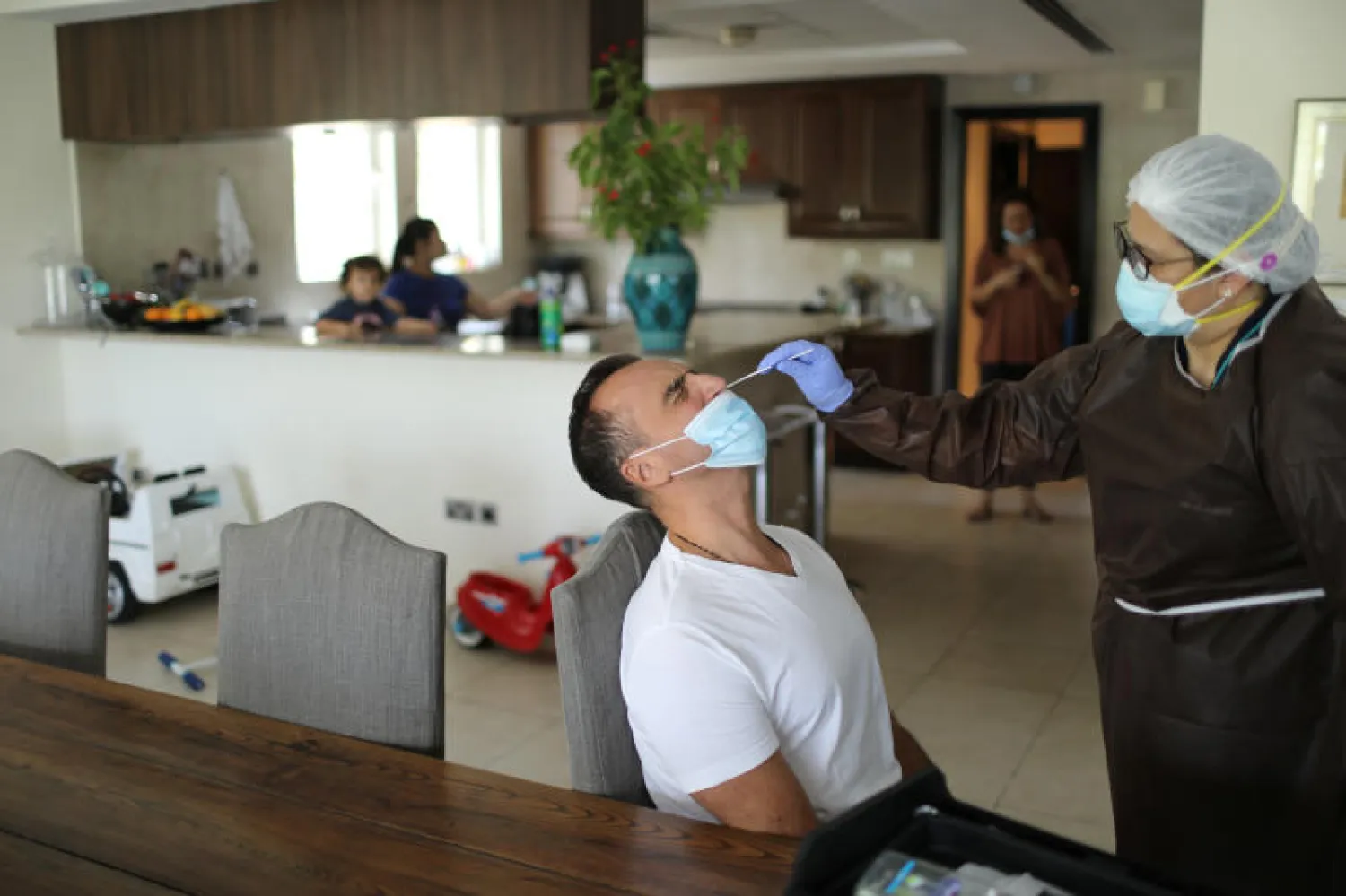 عامل بشركة تجري اختبارات فيروس كورونا للمسافرين في منازلهم يسحب عينة من أحد الأشخاص في دبي (رويترز)