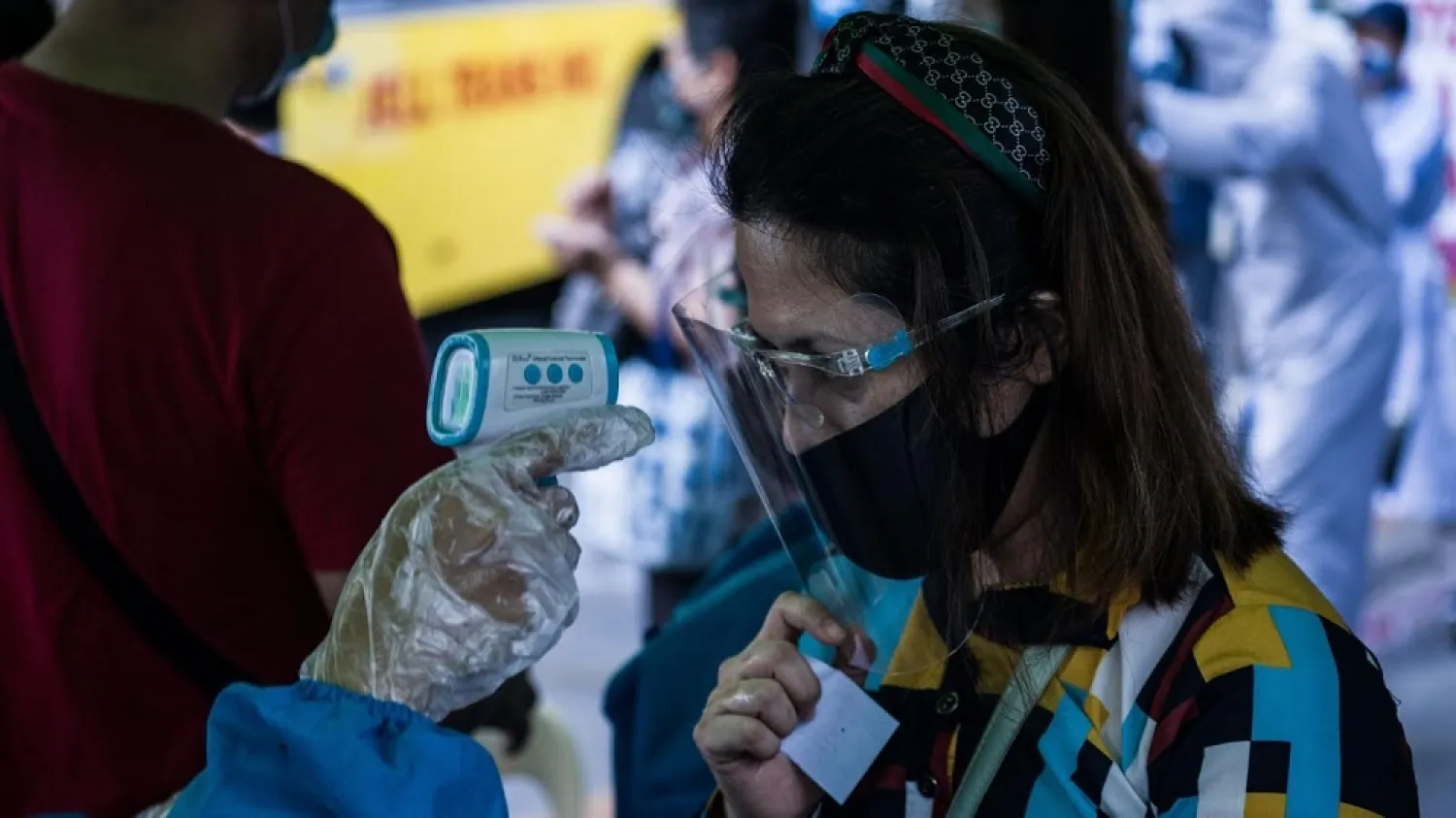 A train passenger has her body temperature taken before boarding a bus at a train station in Manila on July 7, 2020. (AFP)