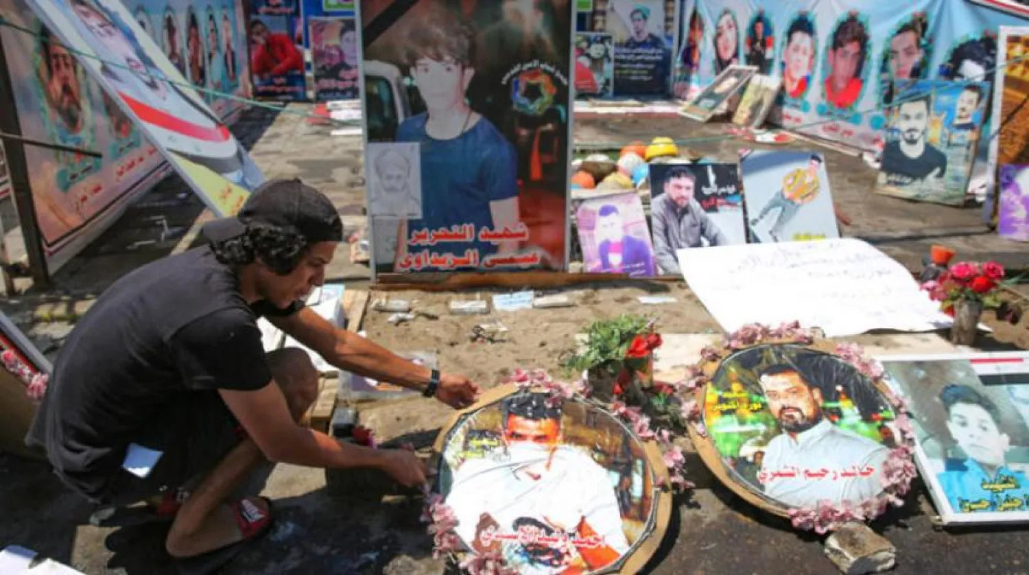 Iraklı bir protestocu Tahrir Meydanı’ındaki gösterilerde hayatlarını kaybedenlerin fotoğraflarını sergiliyor (AFP)