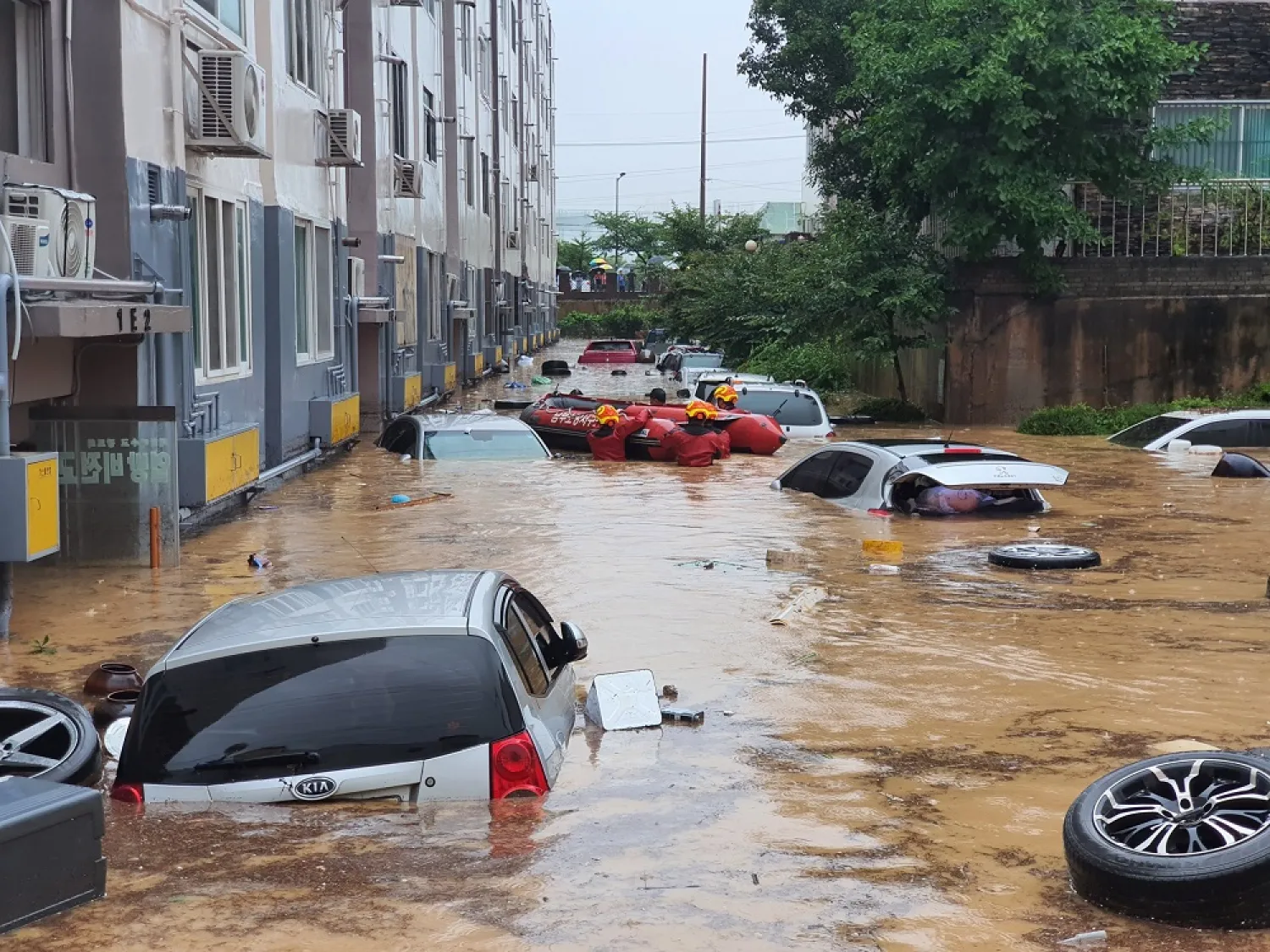 Rescue workers search near vehicles in a parking lot and lower sections of apartment buildings flooded due to heavy rain in Daejeon on July 30, 2020. (AFP)