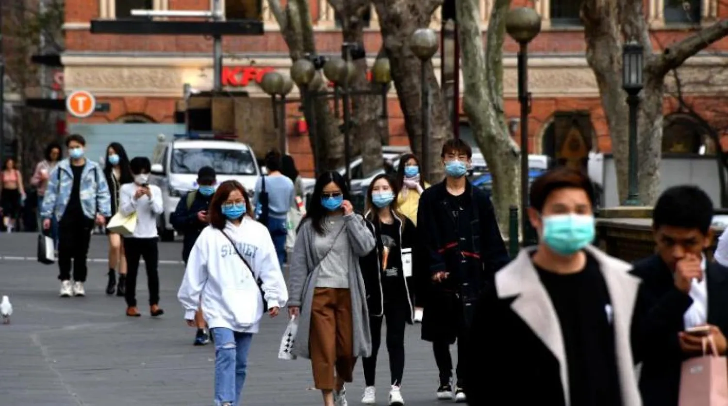 Avustralya’nın Sidney şehrinde sokakta gezen maskeli insanlar (AFP)
