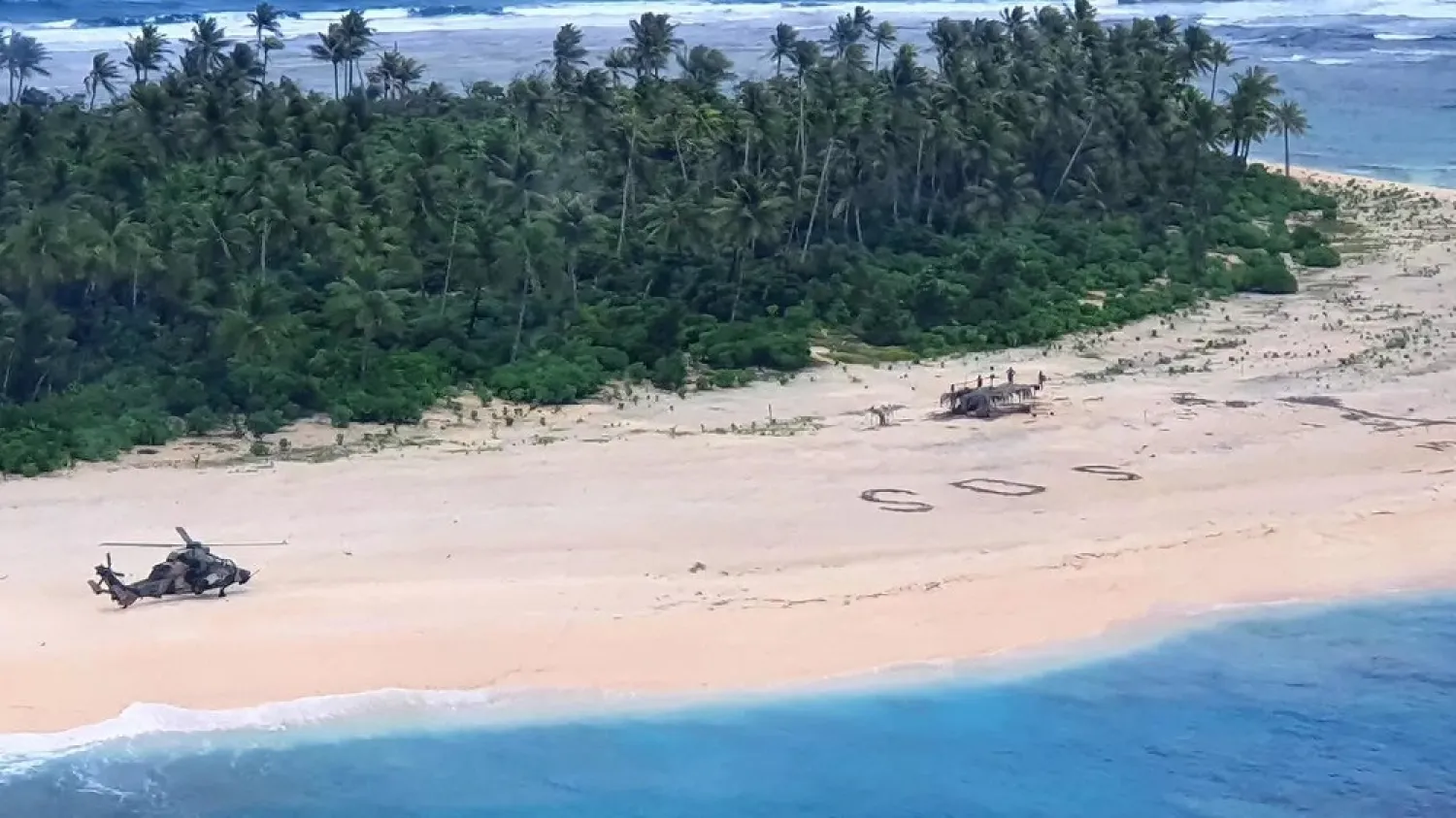 A handout photo from the Australian Defense Force shows a helicopter landing near the letters ‘SOS’ on a beach on Pikelot Island, where the three men were rescued. (AFP)