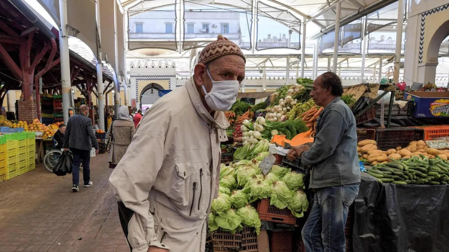 An elderly man wearing a face mask due to the COVID-19 pandemic walks with a crutch at the central market in the Tunisian capital Tunis. (AFP)