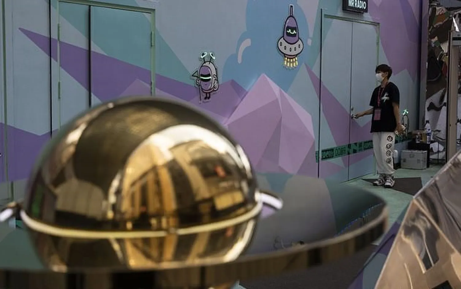 A worker wearing a mask to protect against the coronavirus walks past space themed displays promoting an online service in Beijing, China on Monday, Aug. 3, 2020. An outbreak in China's far northwestern region of Xinjiang is continuing to subside. (AP Photo/Ng Han Guan)

