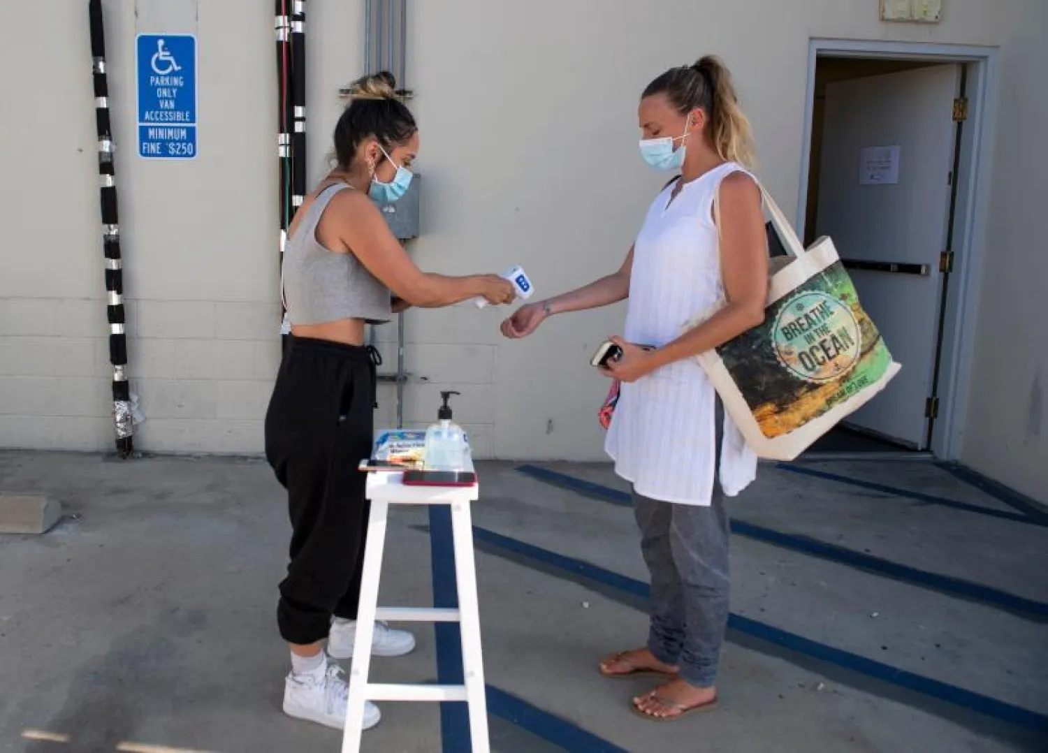 سيدة تعقم وتتحقق من الحرارة  في كاليفورنيا (أ.ف.ب)