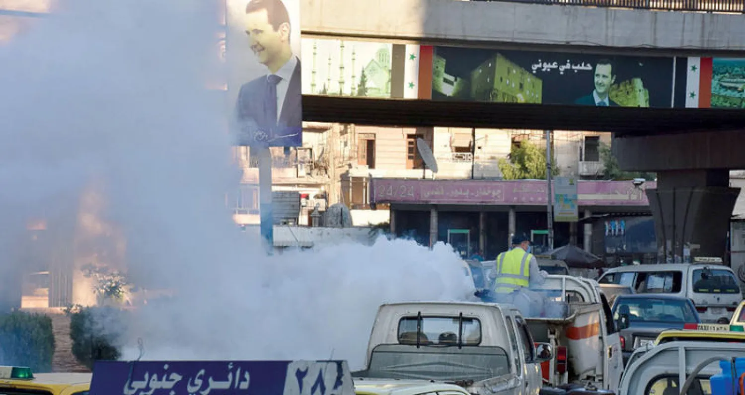 عمال من بلدية حلب يعقمون أحد شوارع المدينة أمس (أ.ف.ب)