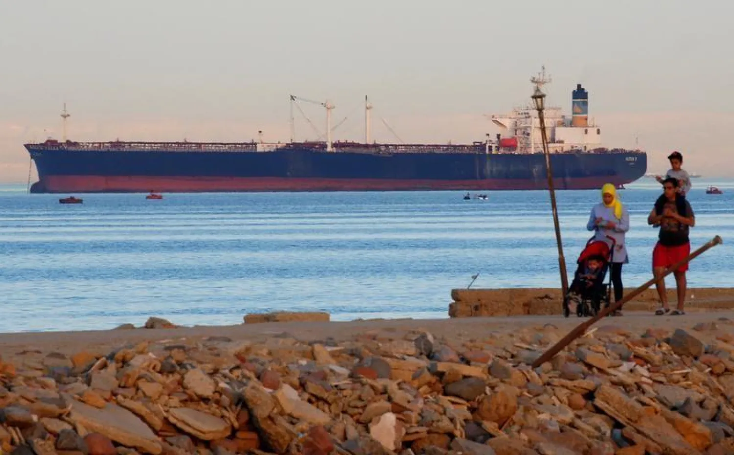 People walk on the beach as a container ship crosses the Gulf of Suez towards the Red Sea before entering the Suez Canal, in El Ain El Sokhna in Suez, east of Cairo, Egypt April 24, 2017. Picture taken April 24, 2017. REUTERS/Amr Abdallah Dalsh
