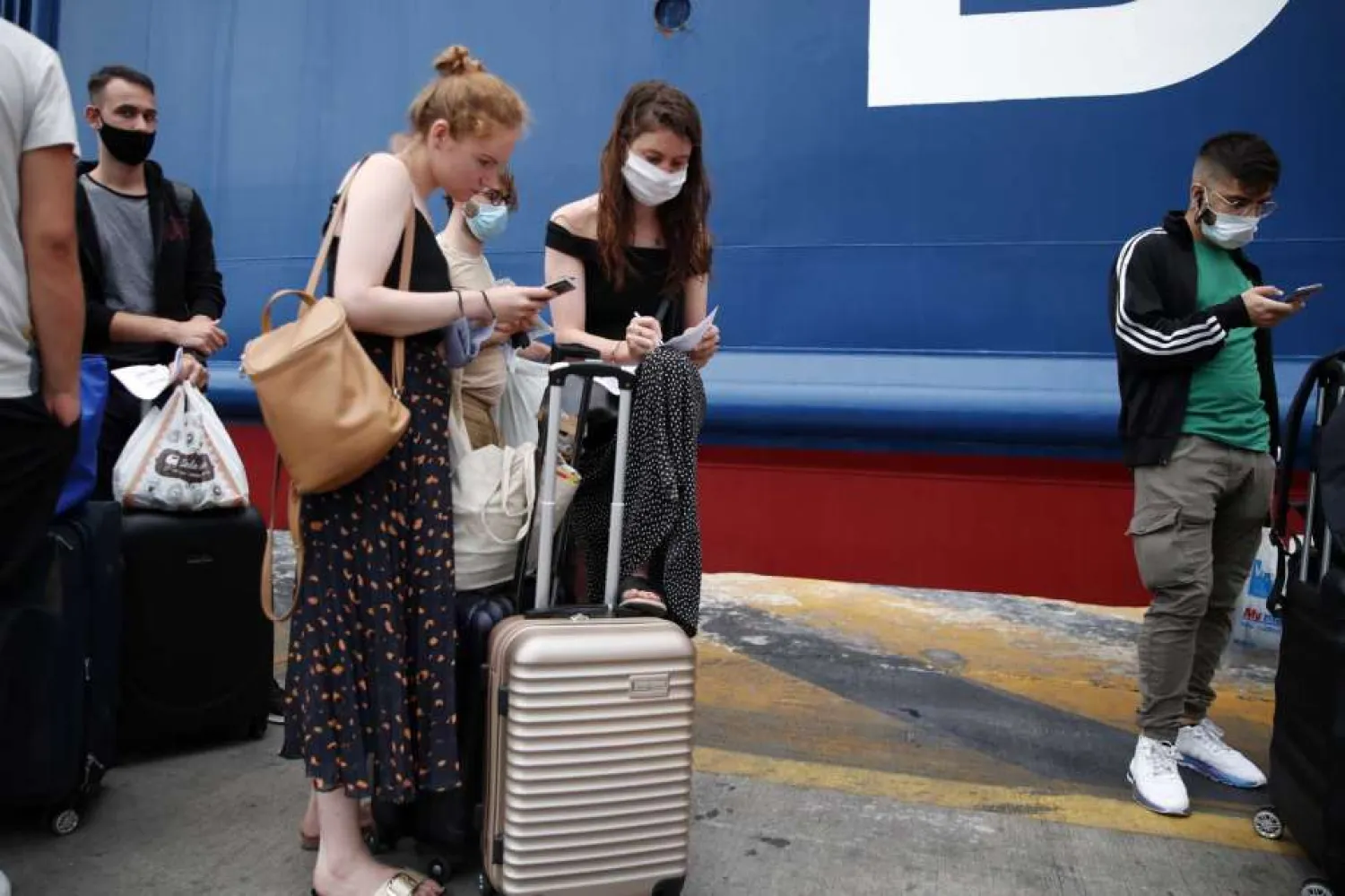People wearing face masks to prevent the spread of coronavirus, fill out a health questionnaire prior to boarding a ferry in the port of Piraeus, near Athens, on Friday, Aug. 7, 2020. (AP Photo/Thanassis Stavrakis)