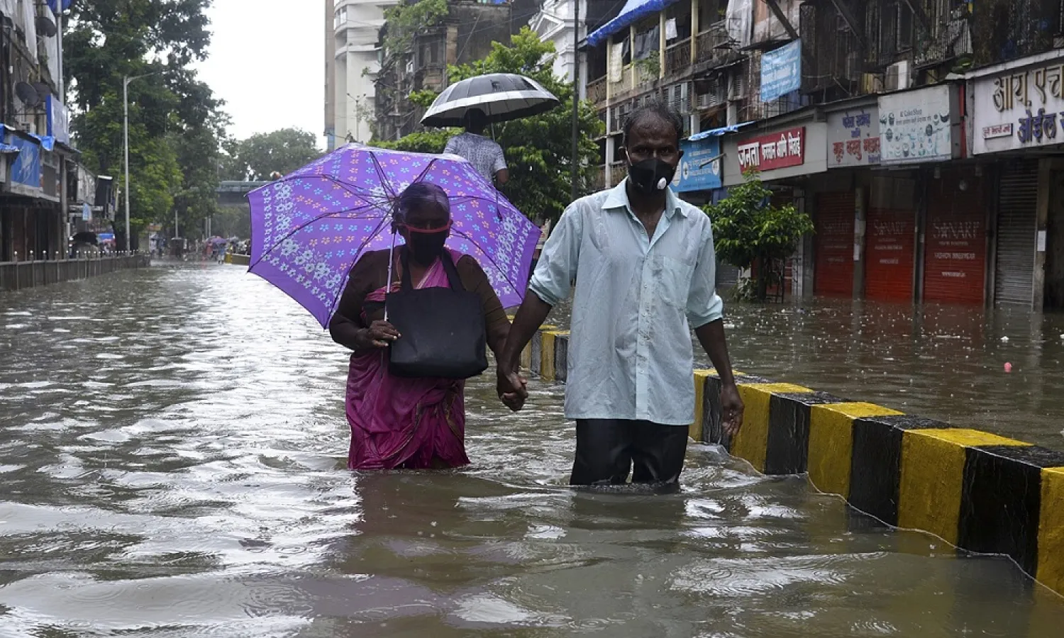 Senior citizens wade in knee-deep water along a flooded road during a heavy monsoon, in Mumbai, India on Tuesday. (AFP)