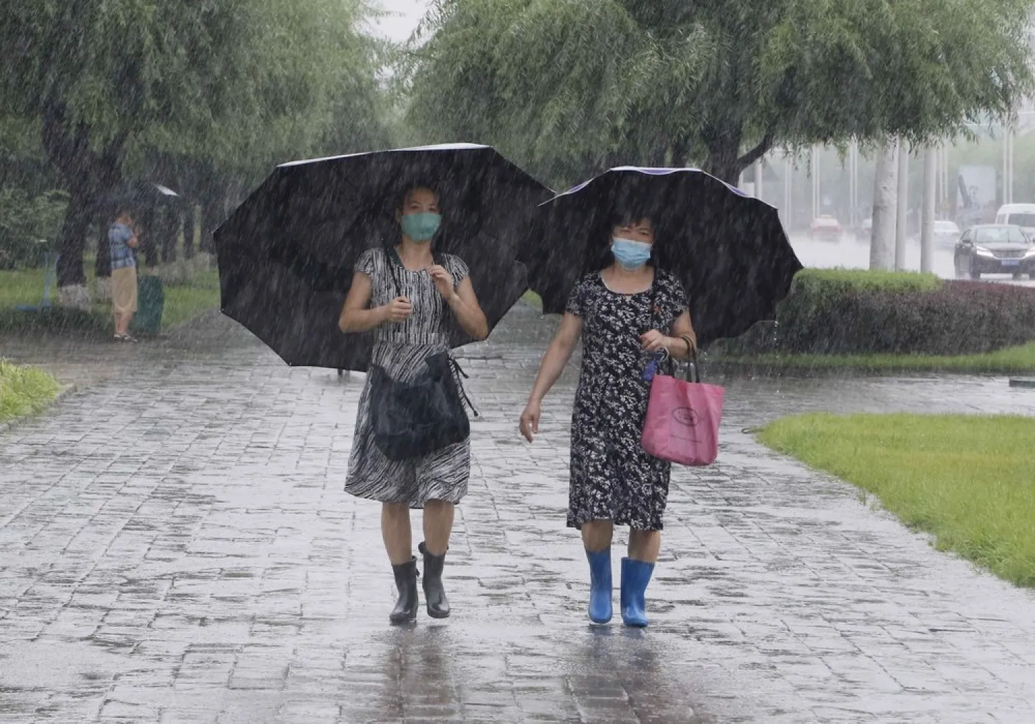 Women walk with umbrellas during torrential rains, Wednesday, August 5, 2020, in Pyongyang. (AP)