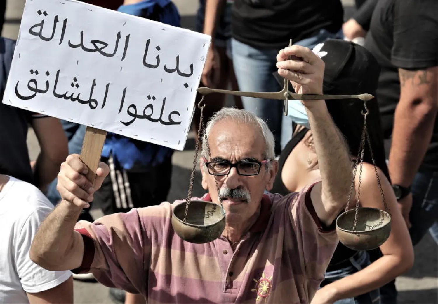 أحد المحتجين في بيروت يحمل لافتة كتب عليها: «نريد العدالة... علقوا المشانق» (إ.ب.أ)