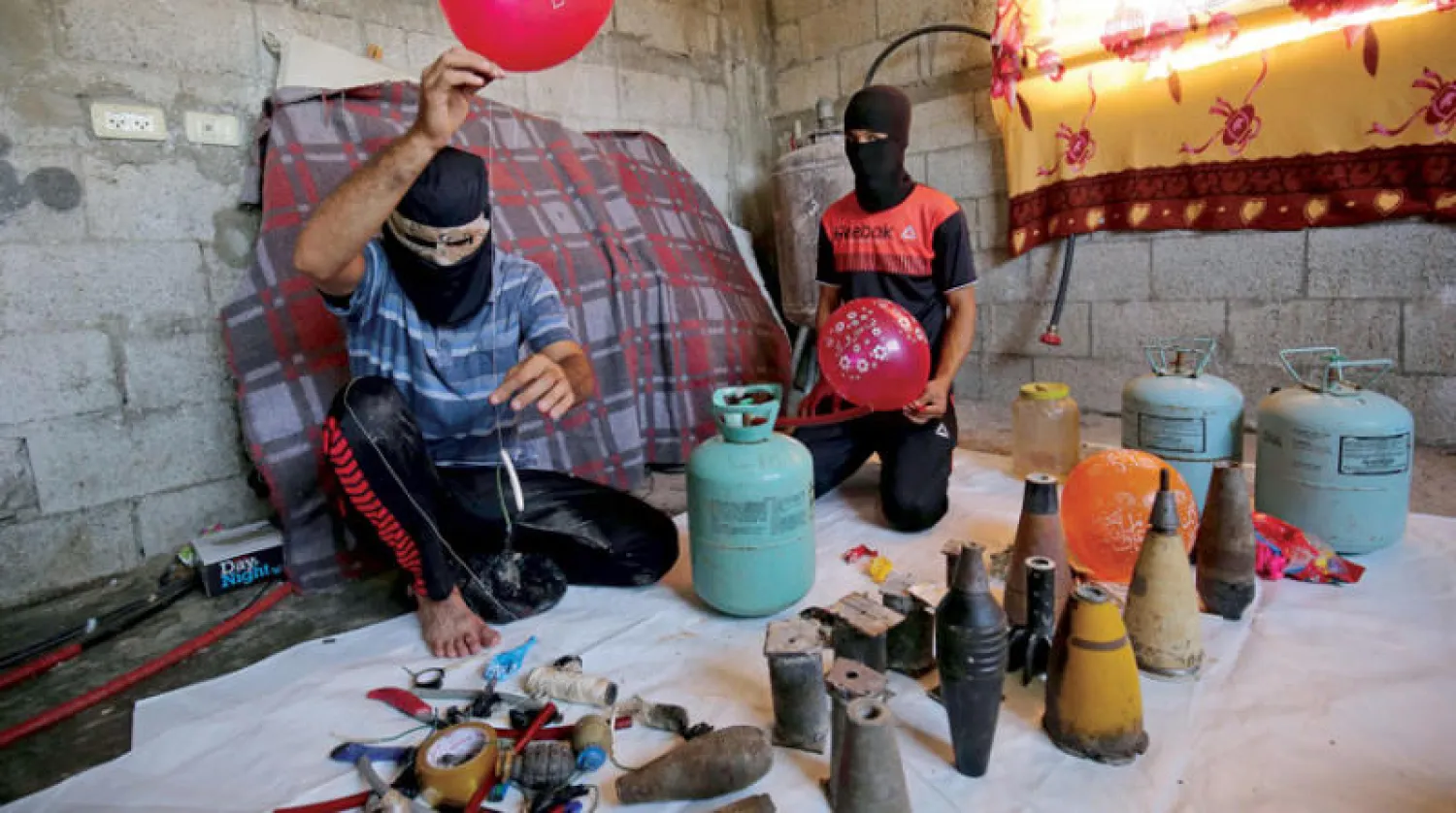 فلسطينيان في رفح يحضّران متفجرات لربطها ببالونات يتم إطلاقها من قطاع غزة في اتجاه المناطق الإسرائيلية القريبة من الحدود (أ.ف.ب)