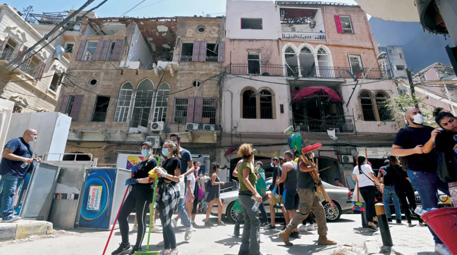 متطوعون ينظفون الركام من أحد الشوارع بين المنازل التي تضررت بسبب الانفجار (أ.ف.ب)