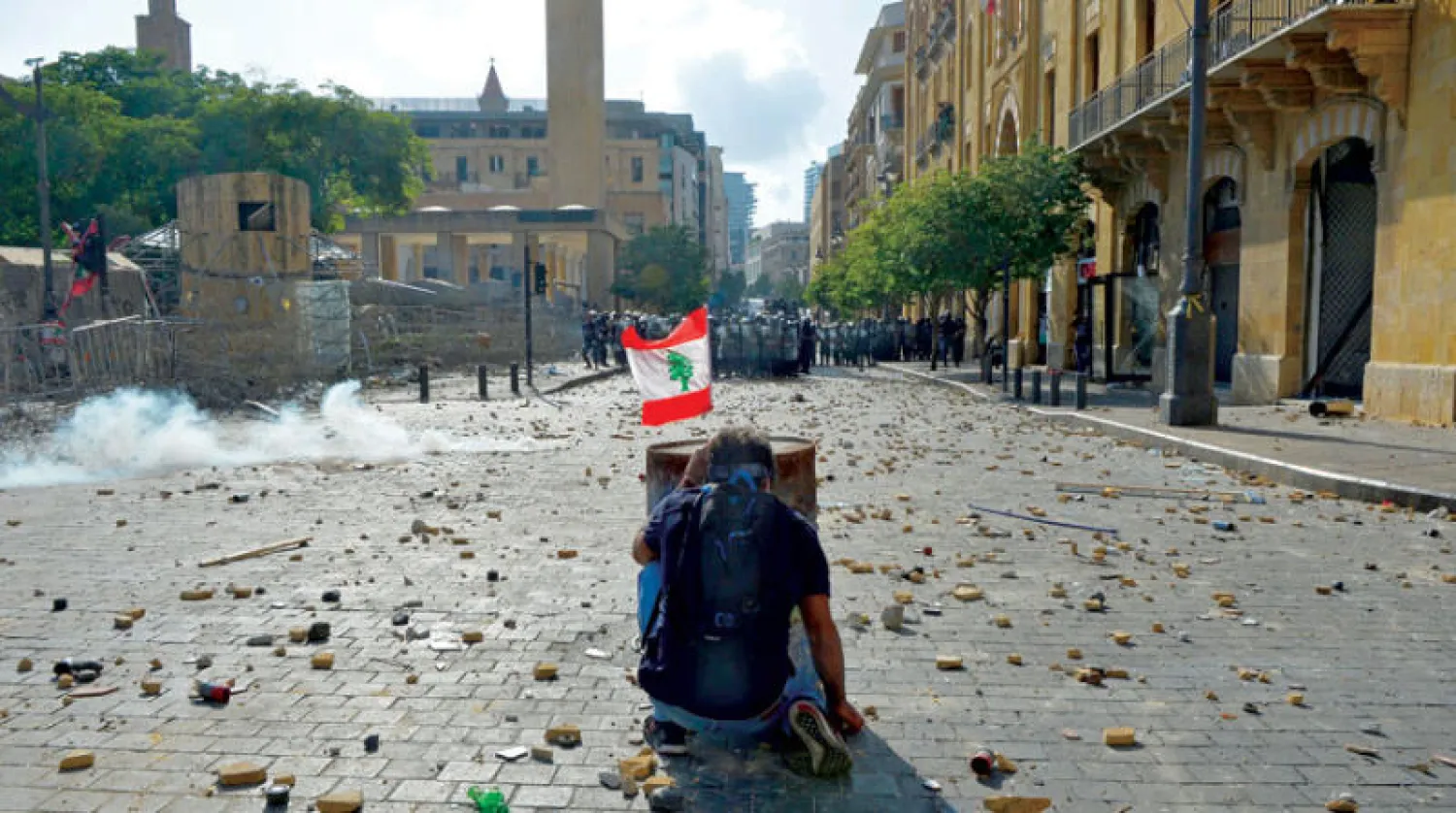 متظاهر أمام البرلمان أمس يحتمي خلف برميل في مواجهة القوات الأمنية (إ.ب.أ)