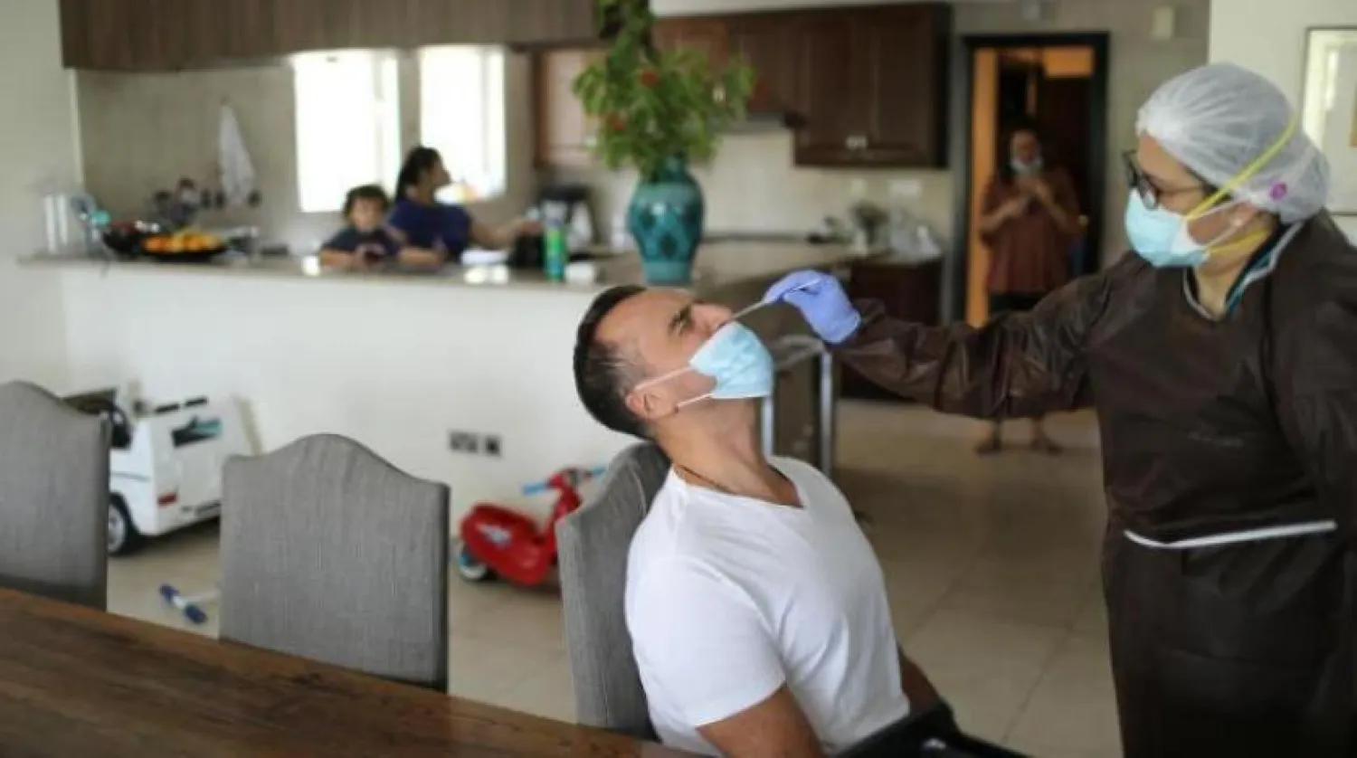 Virüsü testleri yapan bir şirketin çalışanı, Dubai'deki bir kişiden örnek alırken (Reuters)