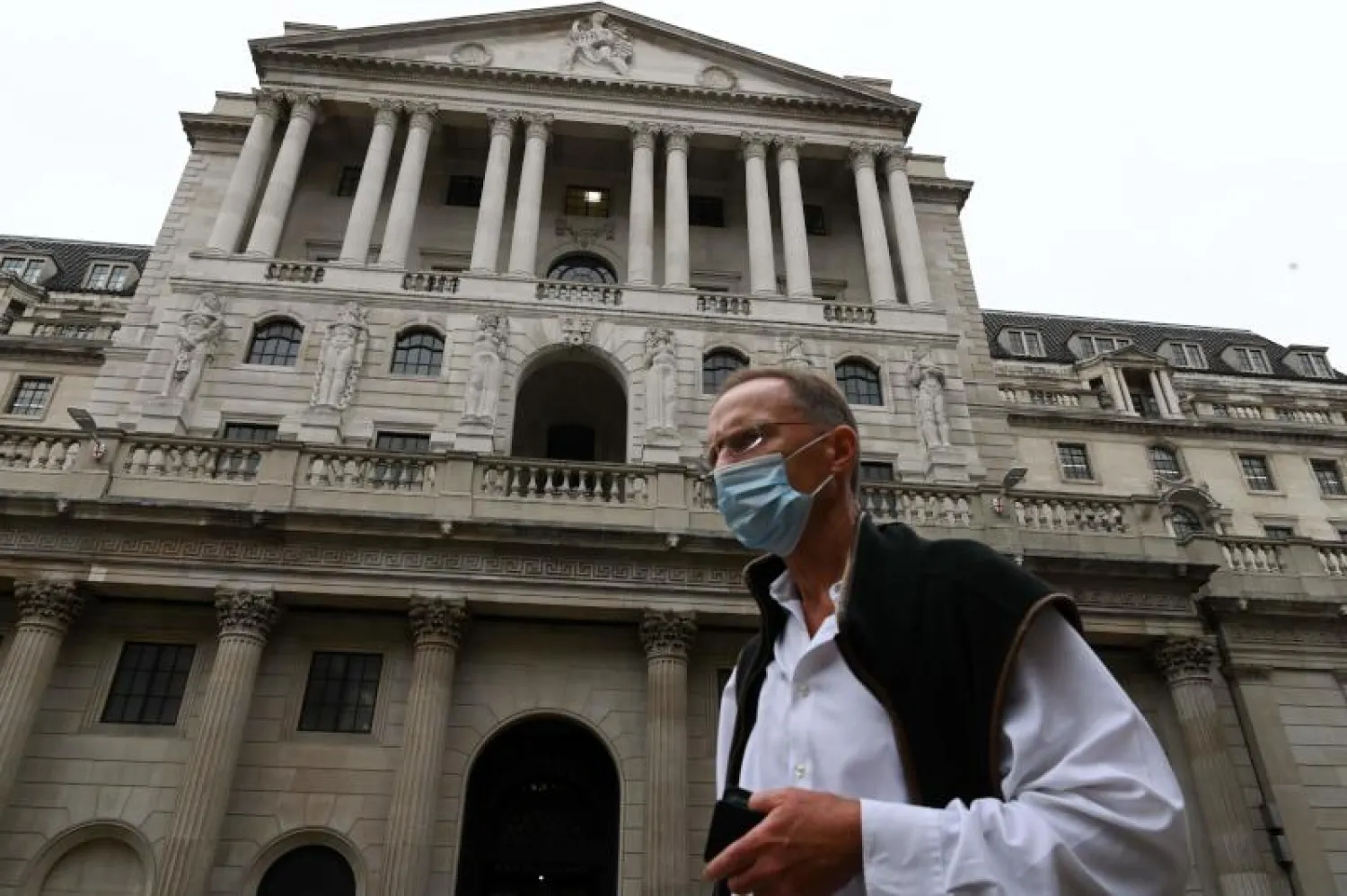 رجل يرتدي كمامة أمام بنك إنجلترا في وسط لندن (أ.ف.ب)