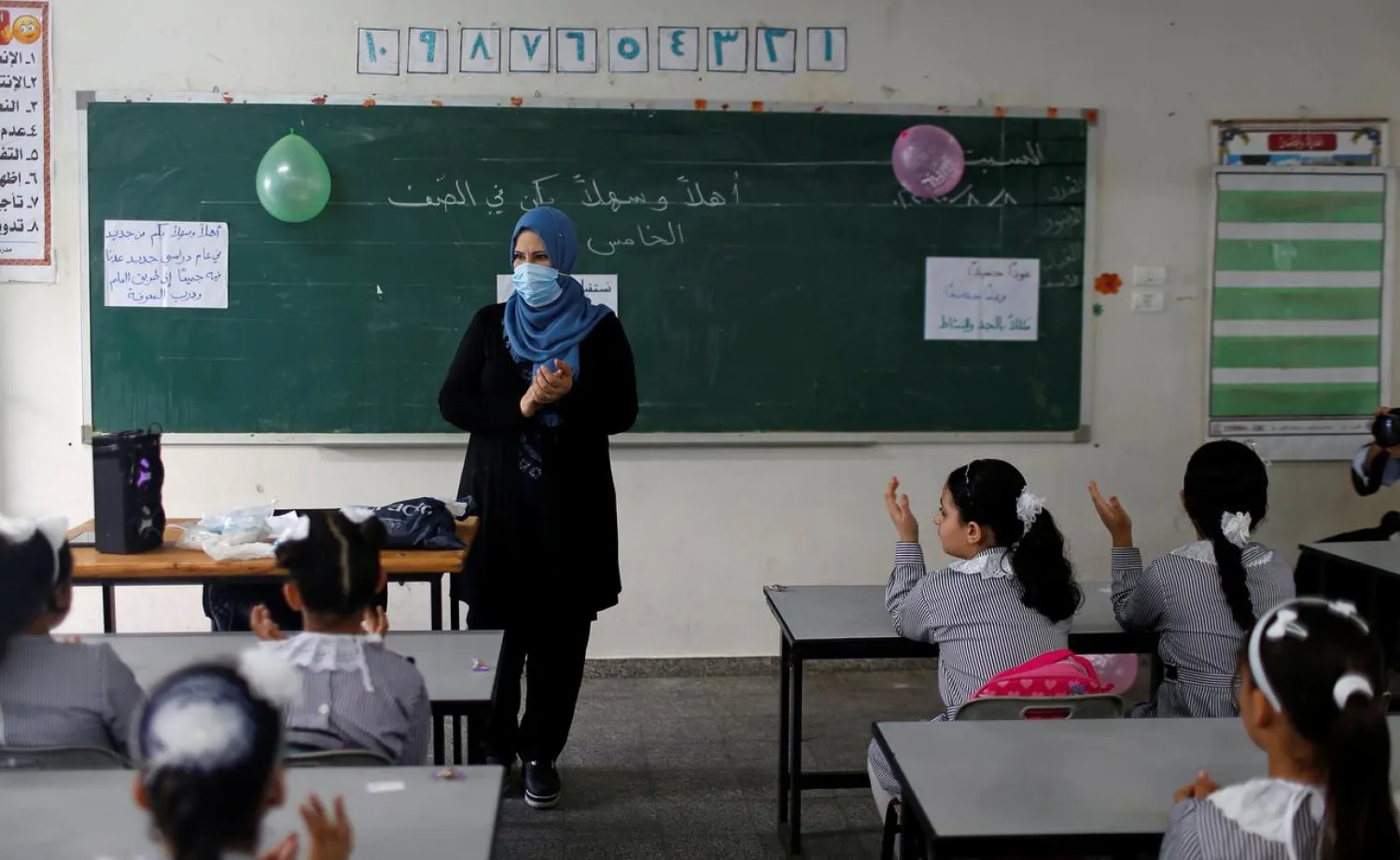 A teacher gestures as Palestinian students sit in a classroom at a UN-run school as a new school year begins amid concerns about the spread of the coronavirus, in Gaza City August 8, 2020. (Reuters)