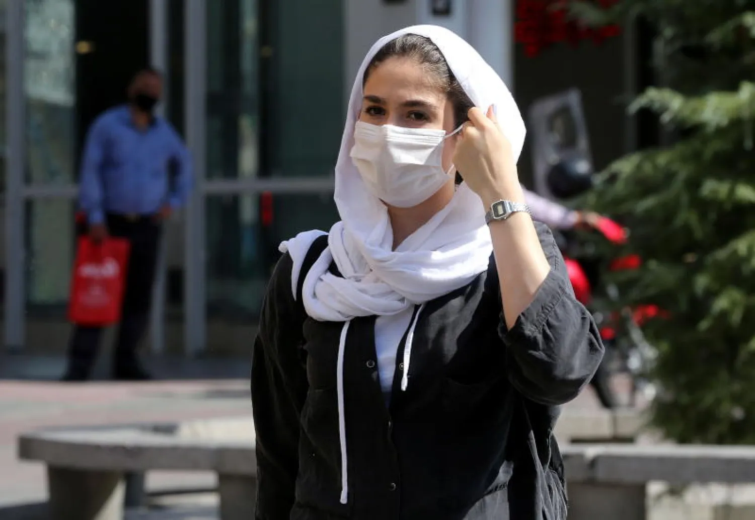 سيدة إيرانية ترتدي قناعاً للوجه وتسير في أحد شوارع طهران (إ.ب.أ)