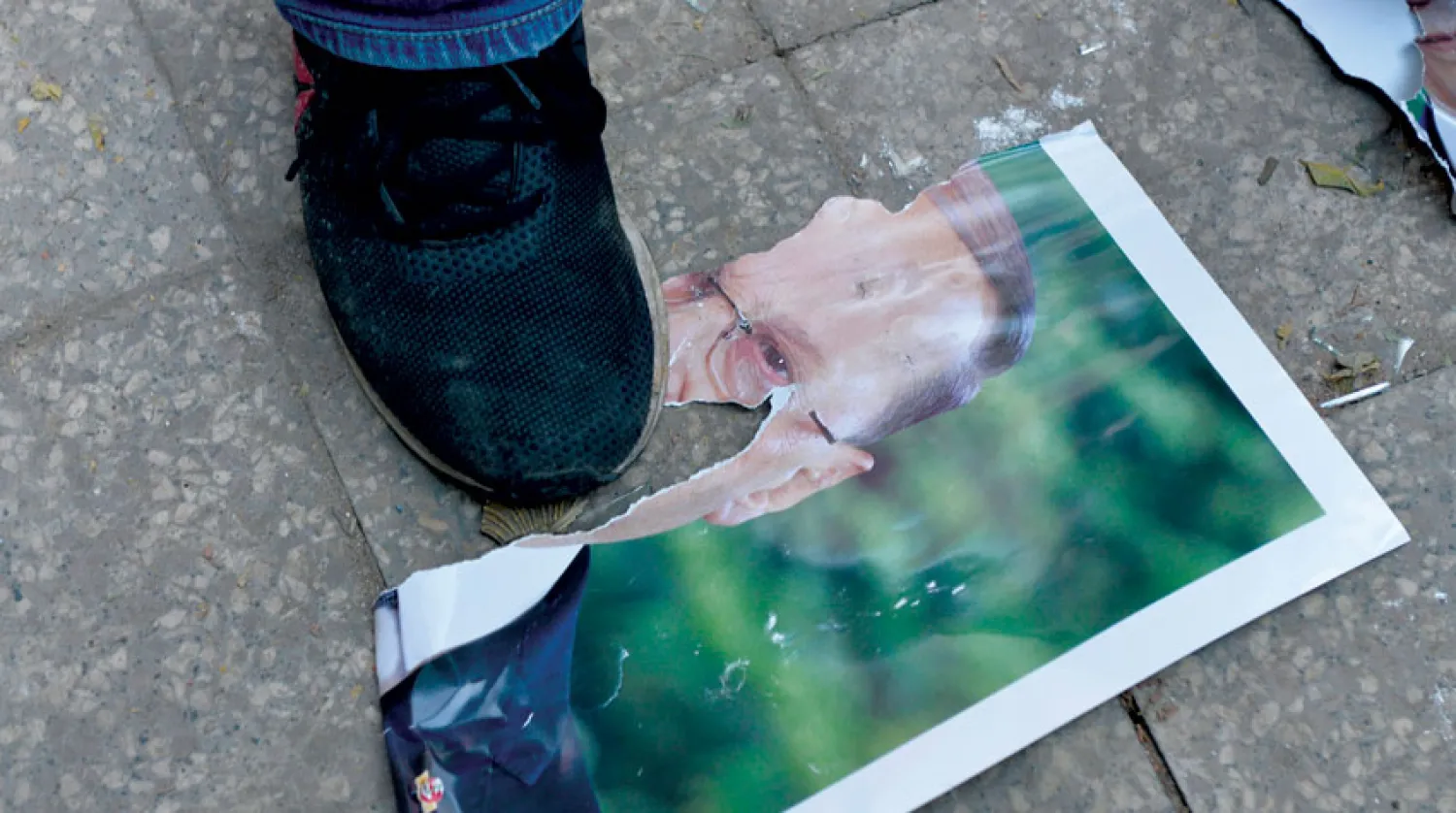 متظاهر يدوس على صورة للرئيس ميشال عون (إ.ب.أ)