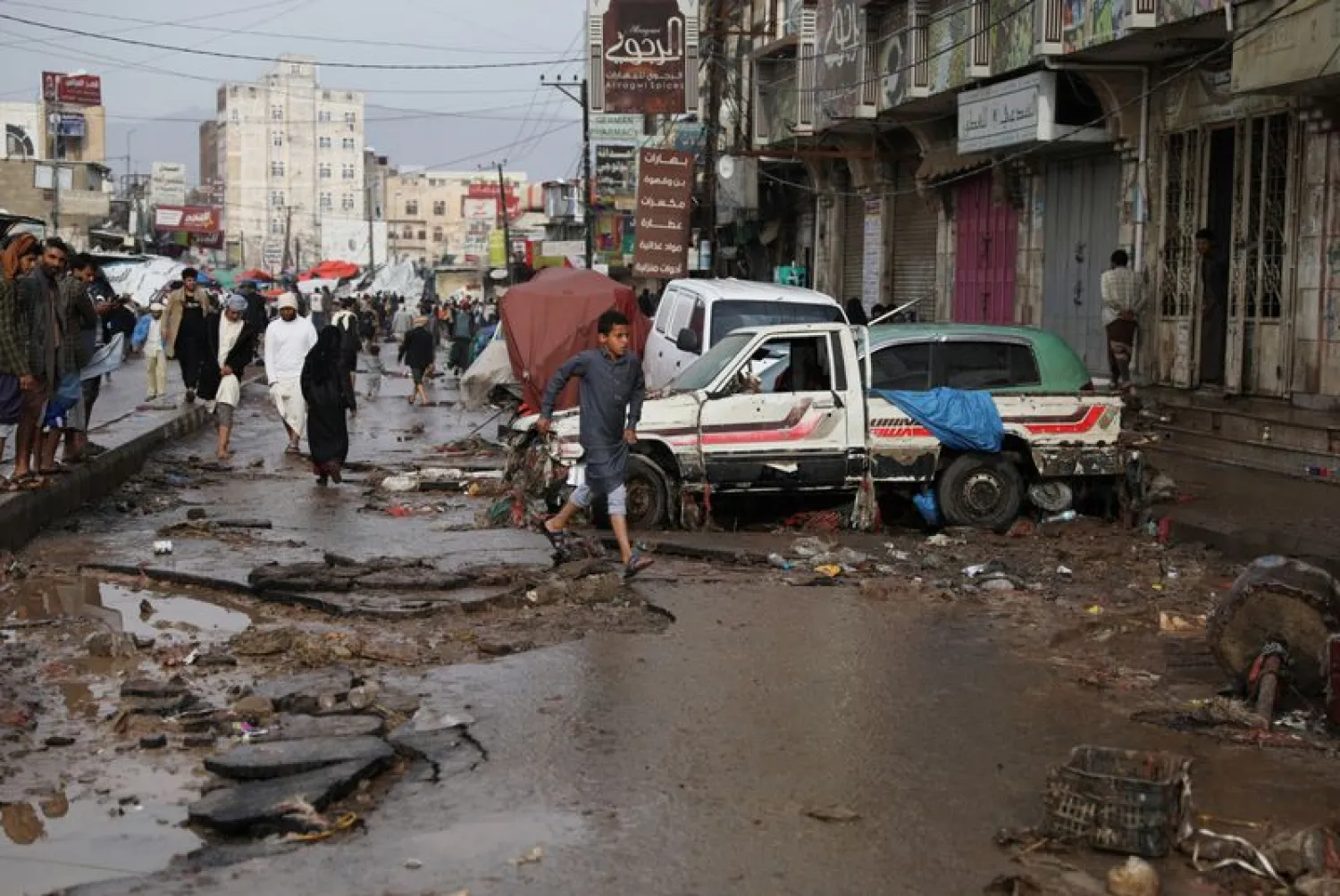 People walk on a damaged street at an area flooded by heavy rains in Sanaa, Yemen (Reuters) 
