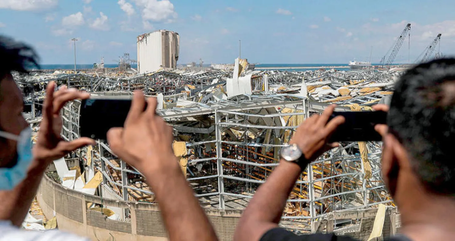 لبنانيان يوثقان الدمار في المرفأ بجواليهما (أ.ف.ب)