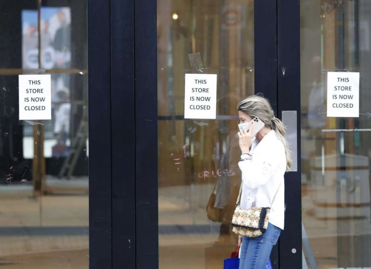 A woman walks by a closed store, in London, Thursday, July 16, 2020. Unemployment across the UK has held steady during the coronavirus lockdown as a result of a government salary support scheme, but there are clear signals emerging that job losses will skyrocket over coming months. The Office for National Statistics said Thursday there were 649,000 fewer people, or 2.2%, on payroll in June when compared with March when the lockdown restrictions were imposed. (AP Photo/Alastair Grant)