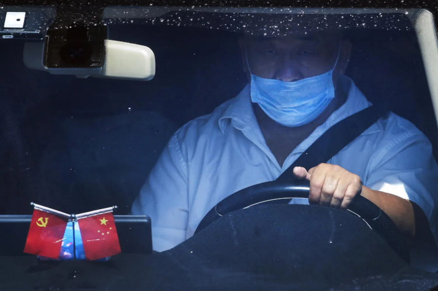 رجل يضع قناع الوقاية داخل سيارته في بكين (أ.ب)