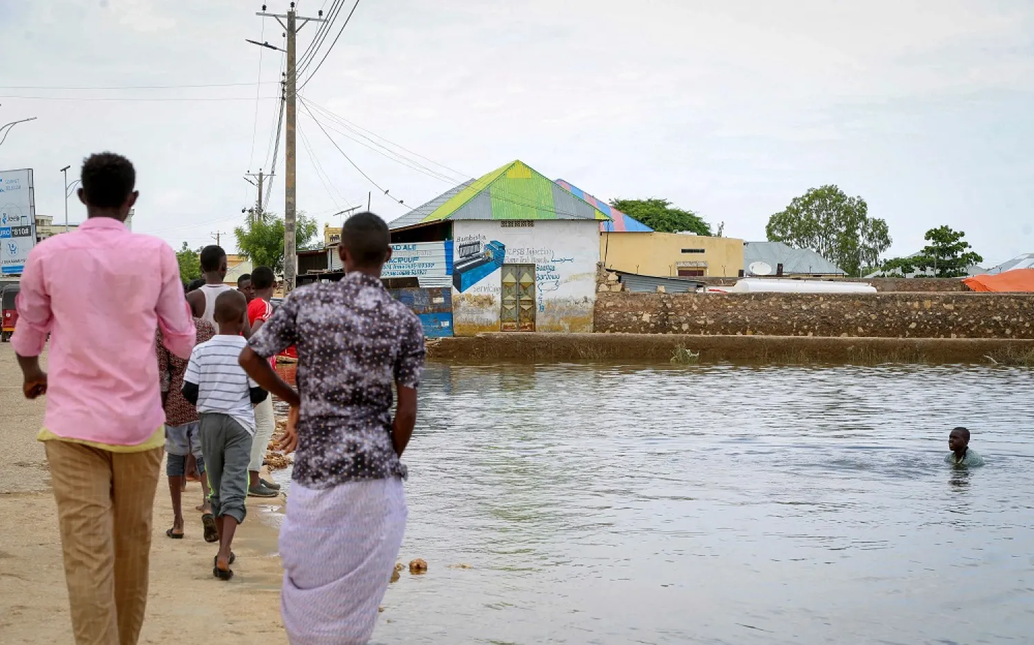 A child swims in the floodwaters as others walk past in the town of Beledweyne, in central Somalia, Nov. 4, 2019. (AP)