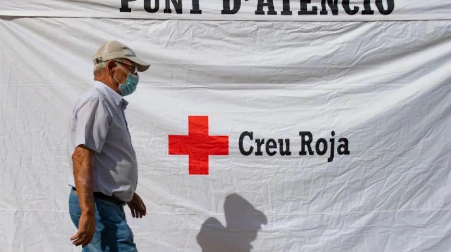 Barselona’da koronavirüs testi yapılan bir çadırın önünde geçen bir adam (AFP)