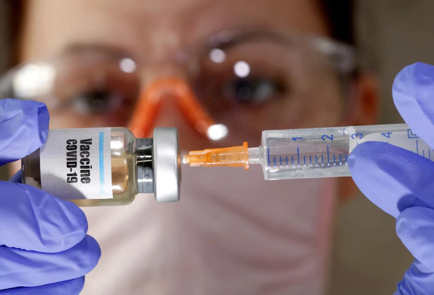 FILE PHOTO: A woman holds a small bottle labeled with a "Vaccine COVID-19" sticker and a medical syringe in this illustration taken April 10, 2020. REUTERS/Dado Ruvic
