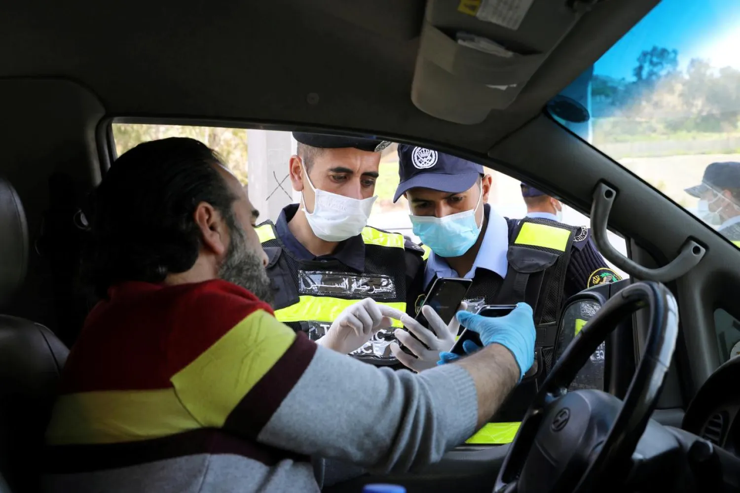 Jordanian policemen check the electronic pass of a driver, amid concerns over the spread of the coronavirus, at a checkpoint in Amman, Jordan April 8, 2020. (Reuters)