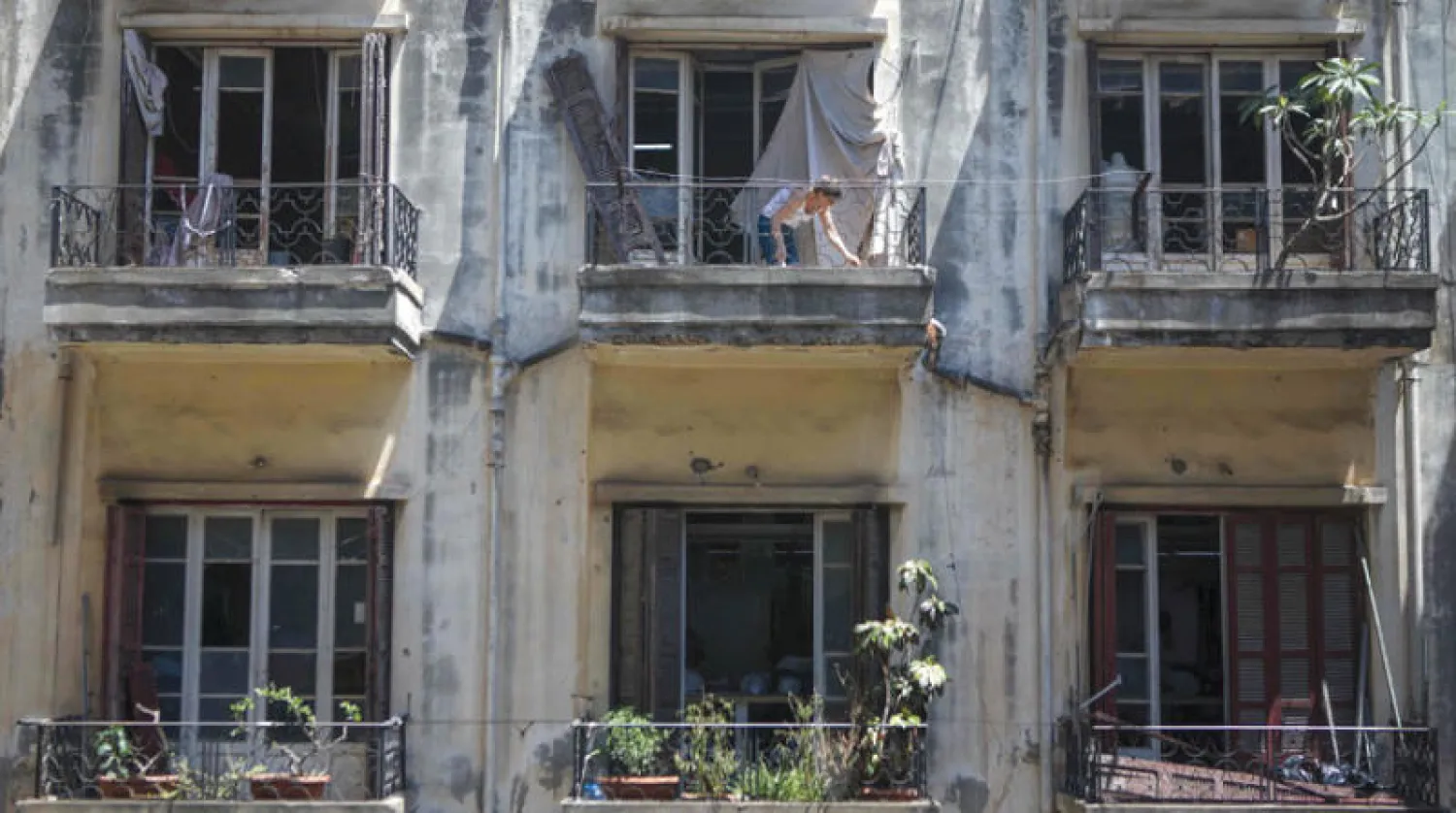 امرأة تزيل الدمار من شقتها في بيروت أمس جراء انفجار المرفأ (أ.ف.ب)