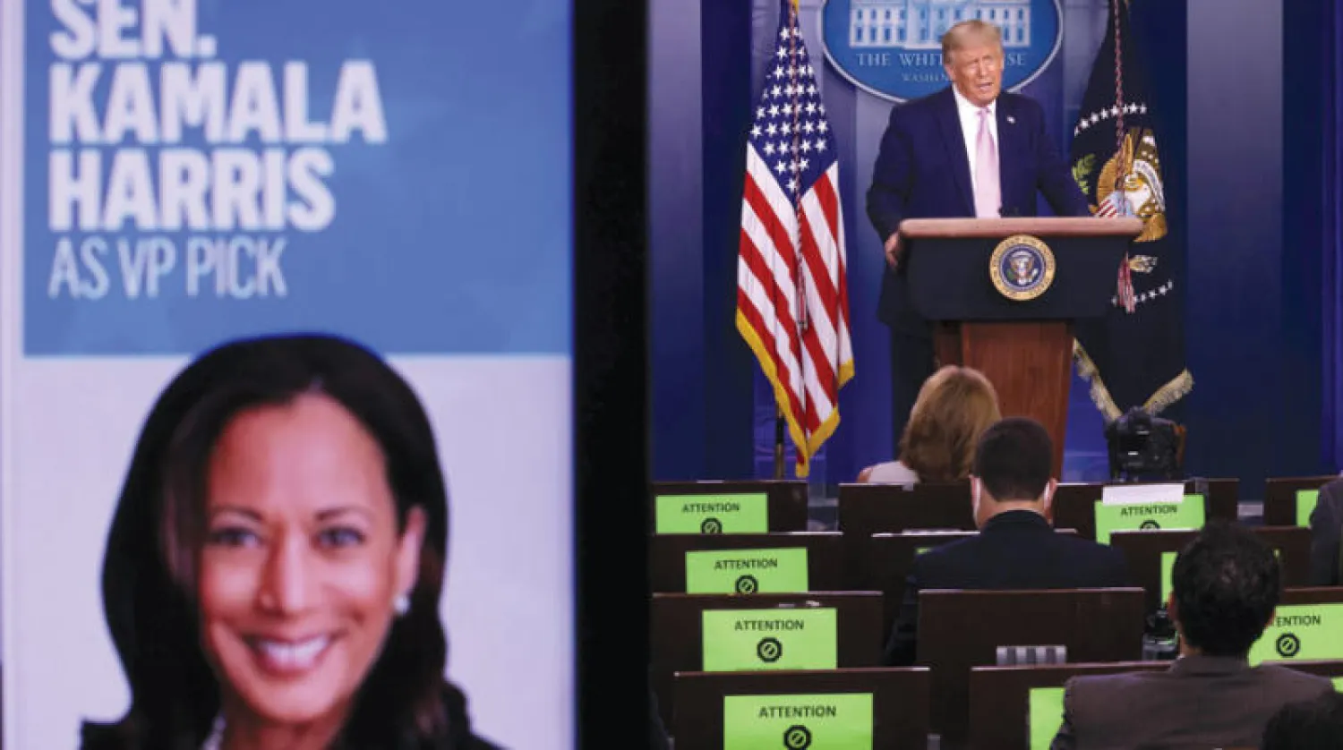 ترمب يتحدث في مؤتمر صحافي وتبدو صورة هاريس ظاهرة على الشاشة نفسها (أ.ف.ب)